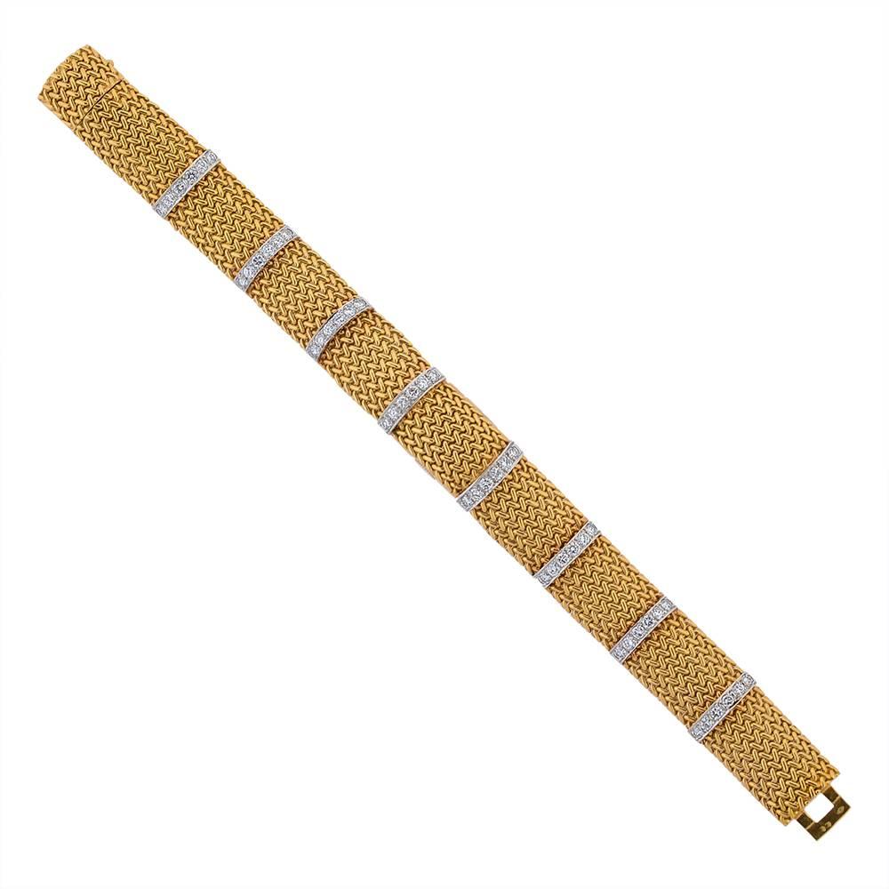A gold and diamond integrated watch bracelet by Cartier, French, designed as an articulated, domed, yellow gold weave bracelet with diamond-set platinum stripes, to a concealed clasp. The centre-most panel lifts to reveal an oblong dial in