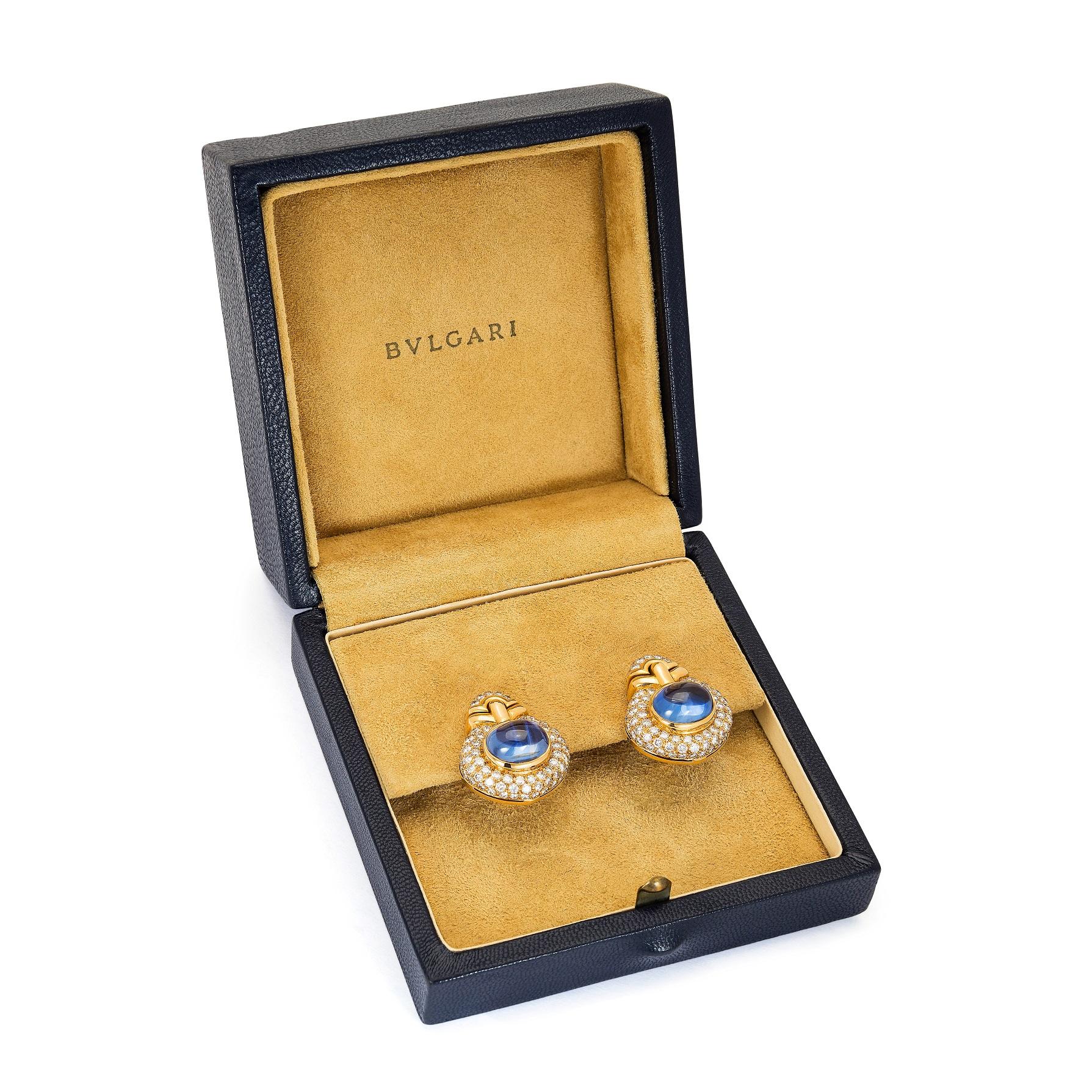 Pair of vintage yellow gold, diamond and sapphire clip-on earrings by Bulgari. Blue cabochon sapphire mounted in 18k yellow gold and surrounded by cluster of diamonds. In original Bulgari box.