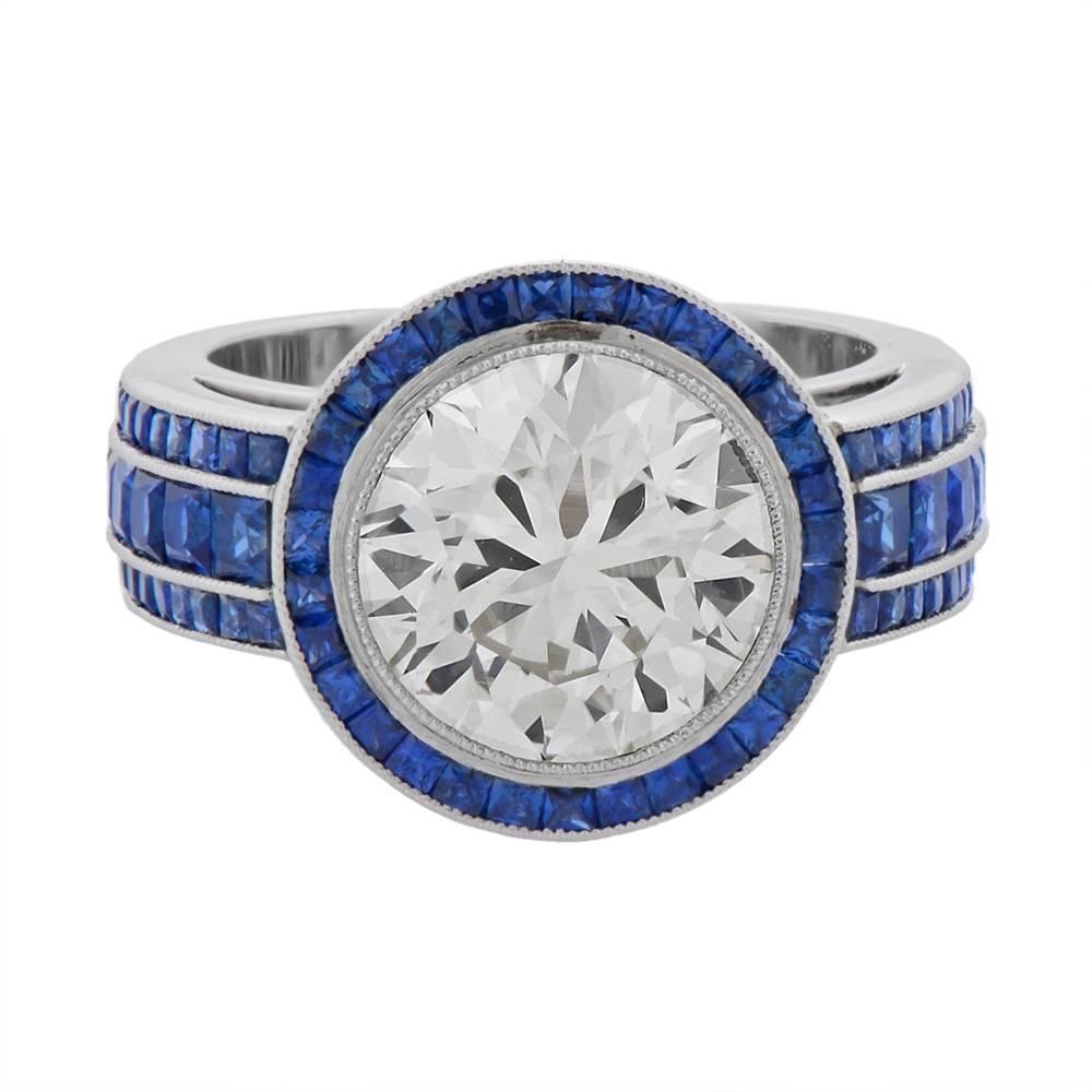 A platinum, diamond and sapphire ring, centring on an impressive, bezel-set, round brilliant-cut diamond, weighing approximately 4cts, the bezel and shoulders channel-set with a total of 2.35cts of calibré French-cut sapphires, mounted in platinum