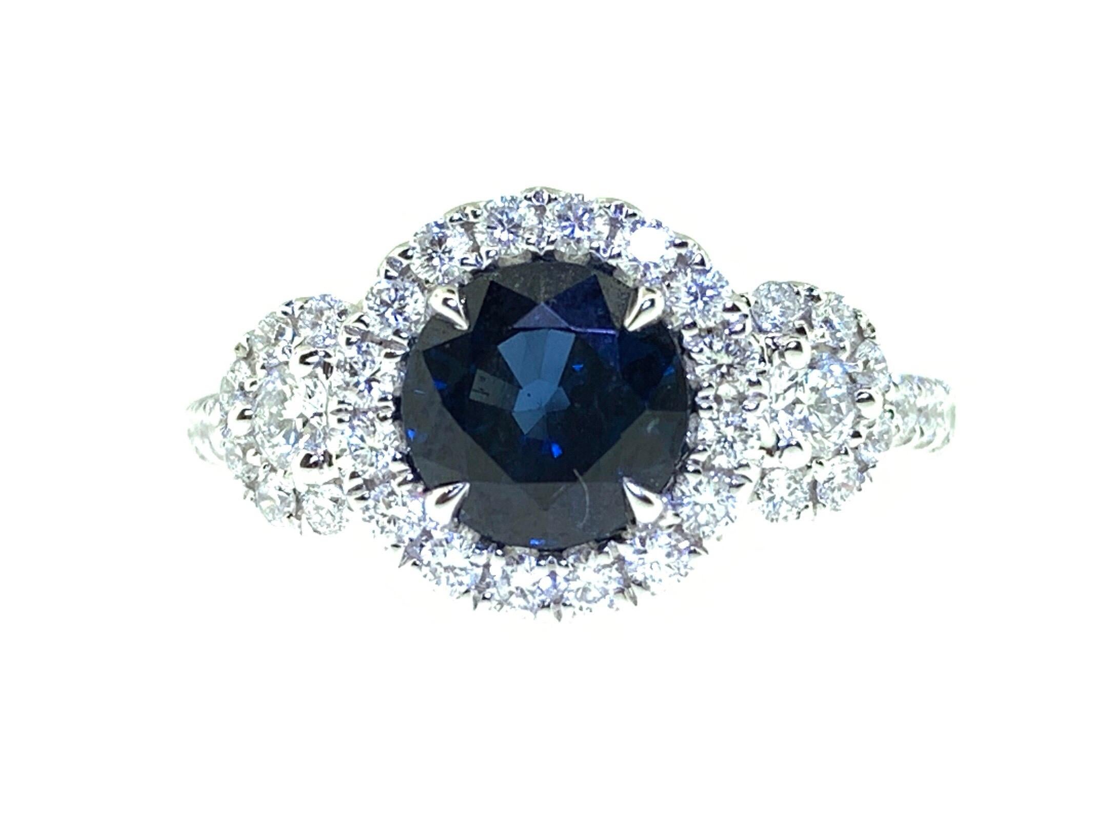 This stunning ring showcases a beautiful 1.65 carat blue round sapphire with a diamond halo set in 18 karat white gold flanked by two pave diamond circles. Total diamond weight = 0.65 carats of diamonds. Ring size is 6 1/2.
