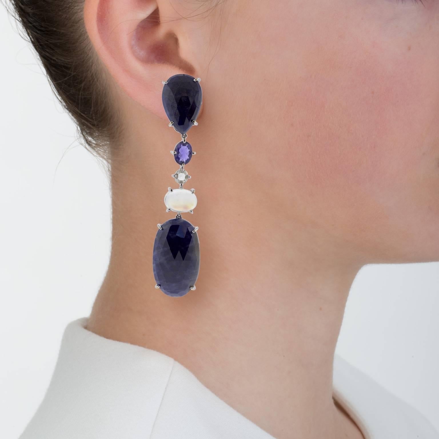 The blue of these opaque sapphires is dark, but the surface faceting lets them glitter mysteriously.

This classic navy and white design is long and dramatic. Paired with diamonds and moonstones the dark blue of these sapphires reads deep and dark,