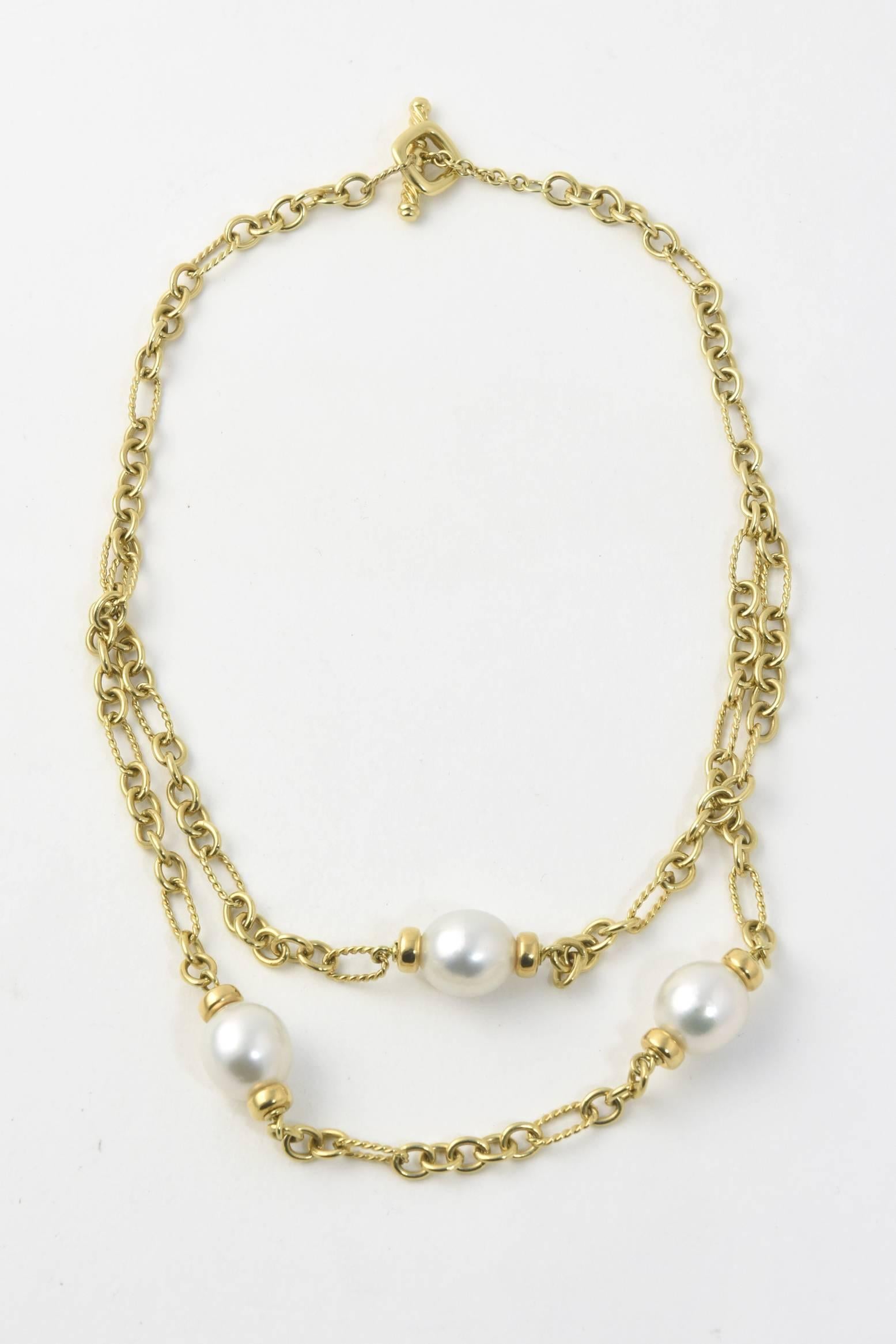 Two tier David Yurman Pearl necklace with  top layer featuring a 12.5mm plus pearl center with gold caps hanging on a chain with oval cable links and smooth chain link terminating in a toggle clasp.  The bottom tier has 2 more pearls that are spaced