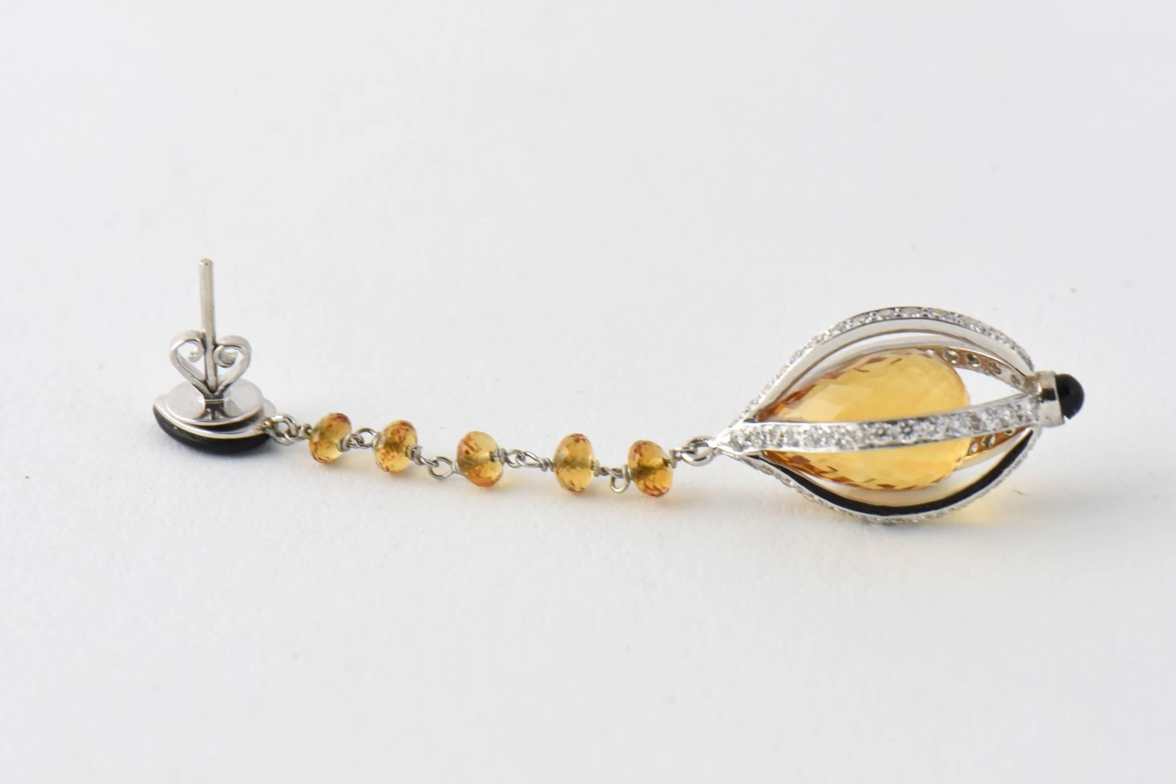 Very long earrings featuring a teardrop diamond and onyx top section with a facetted citrine & white gold chain extending to a citrine briolette in a diamond & 18k white gold cage with a onyx tip.