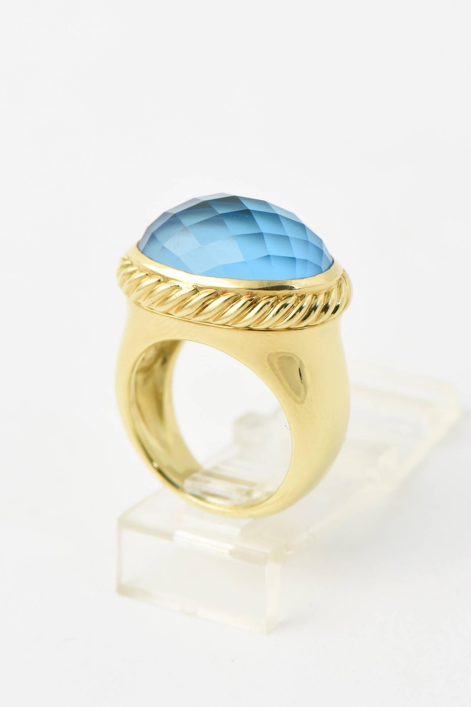 David Yurman 18k yellow gold east - west signature ring with faceted blue topaz mounted in a cable frame. The band is solid gold with a smooth finish.  Marked 