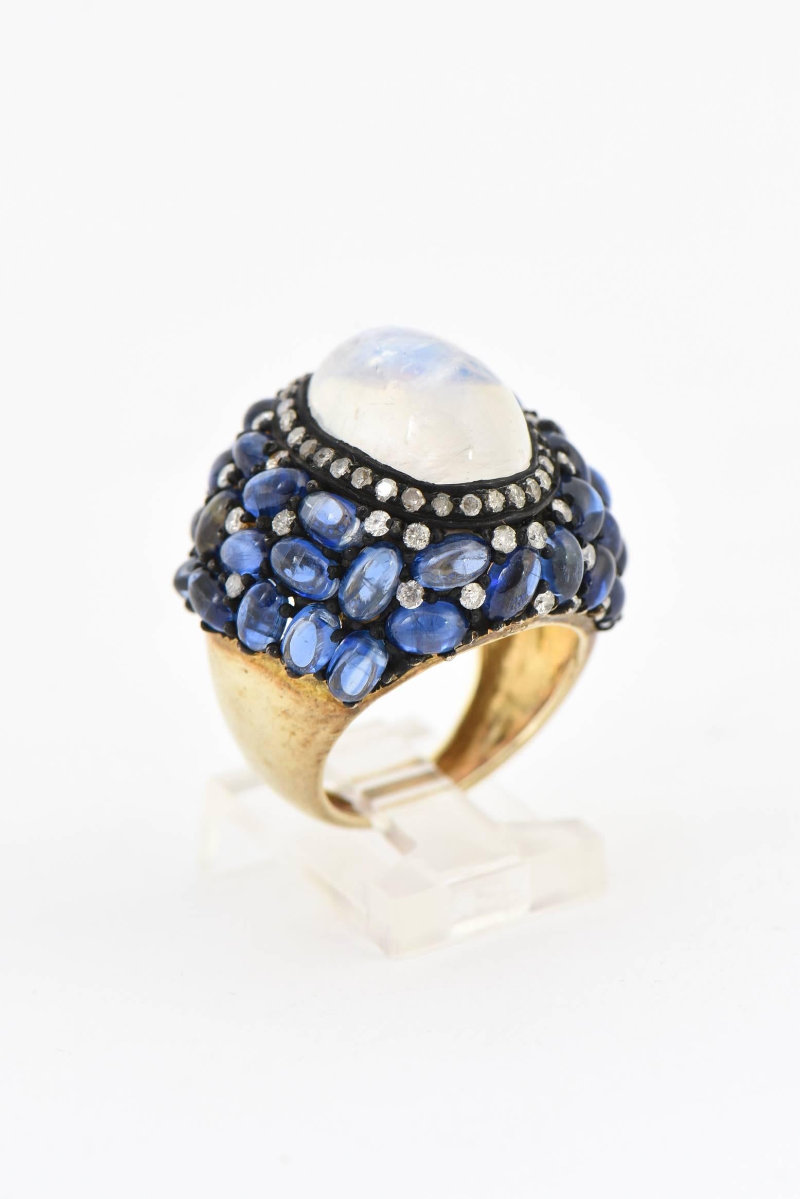 Impressive cocktail ring featuring a centrally set cabochon moonstone with a diamond frame inside a freeform collection of kyanite and diamond design.  This design is set in a sterling silver mounting with an 18k interior band.  The ring measures