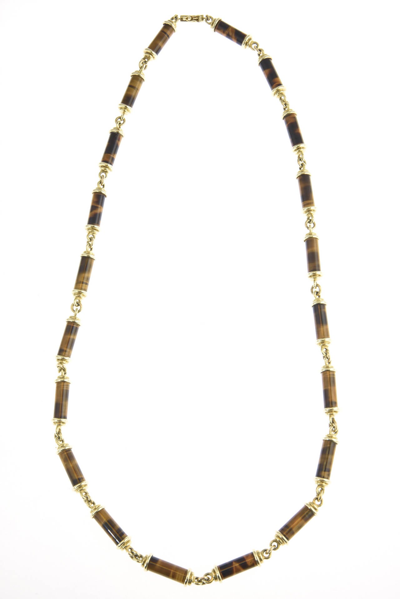 Finely made 14k gold necklace containing Tiger's eye tubes with gold caps linked together by gold rings.
Marked 14k MAT