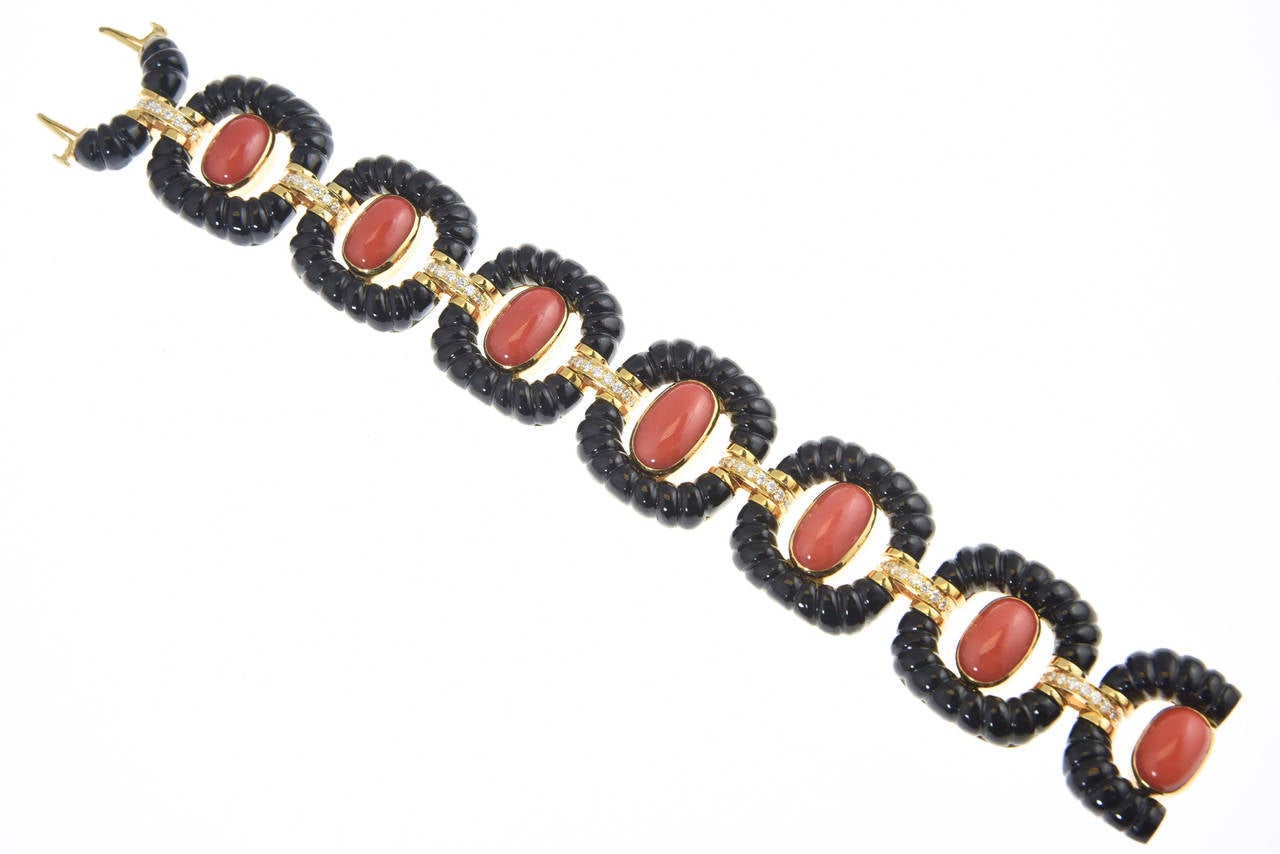 Incredible bracelet with links made of carved onyx frames with oval coral cabochons centers mounted in 14k yellow gold with diamond bars holding the links together.  A beautifully made piece as evident by looking at the back.

Marked 14k