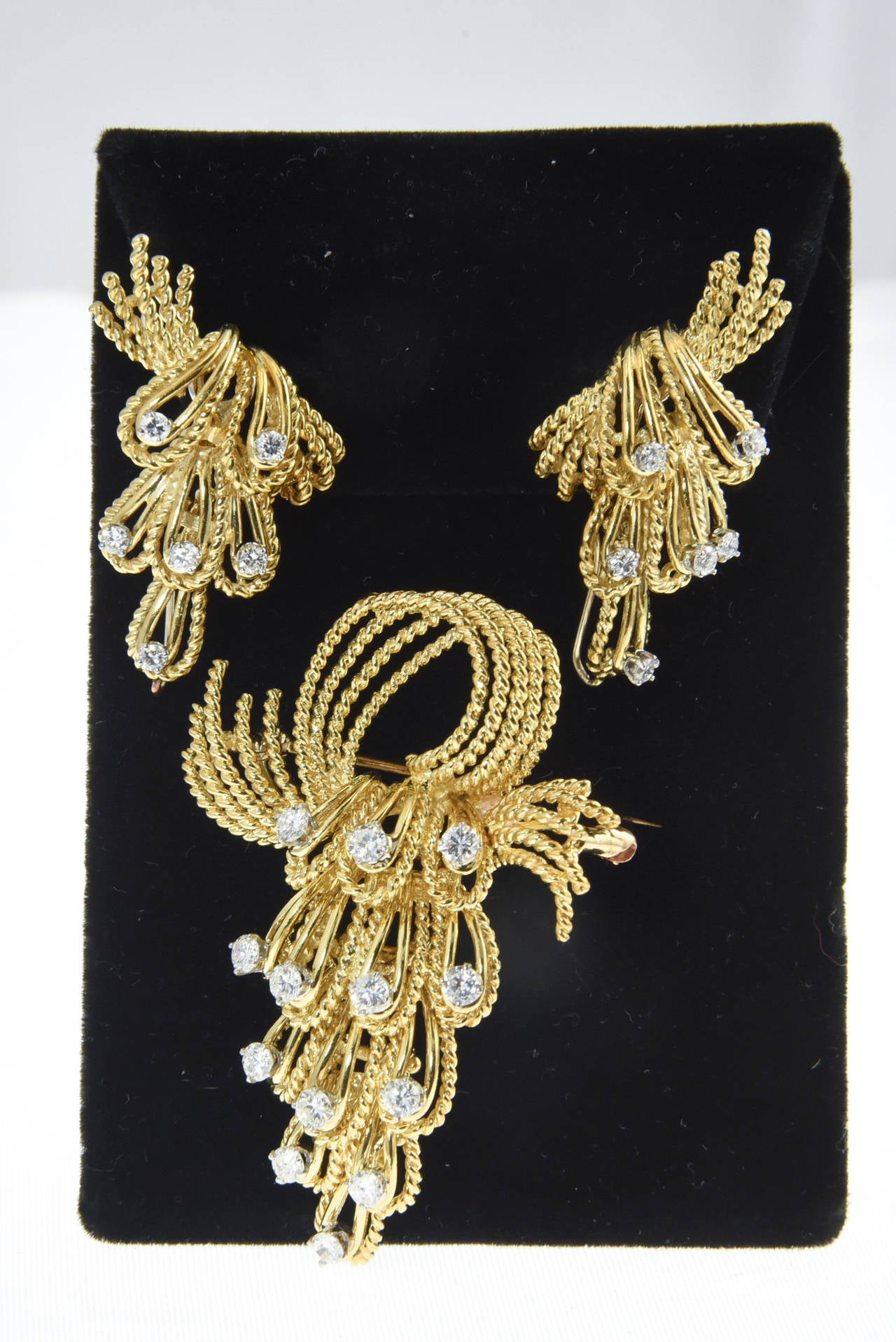 Beautifully made brooch and earrings with cascading diamonds amongst twisted and shiny 18k gold loops.

The earrings are clip ons (NO post).  They have a wire on the bottom that you can drop something from for example a South Seas Pearl. 