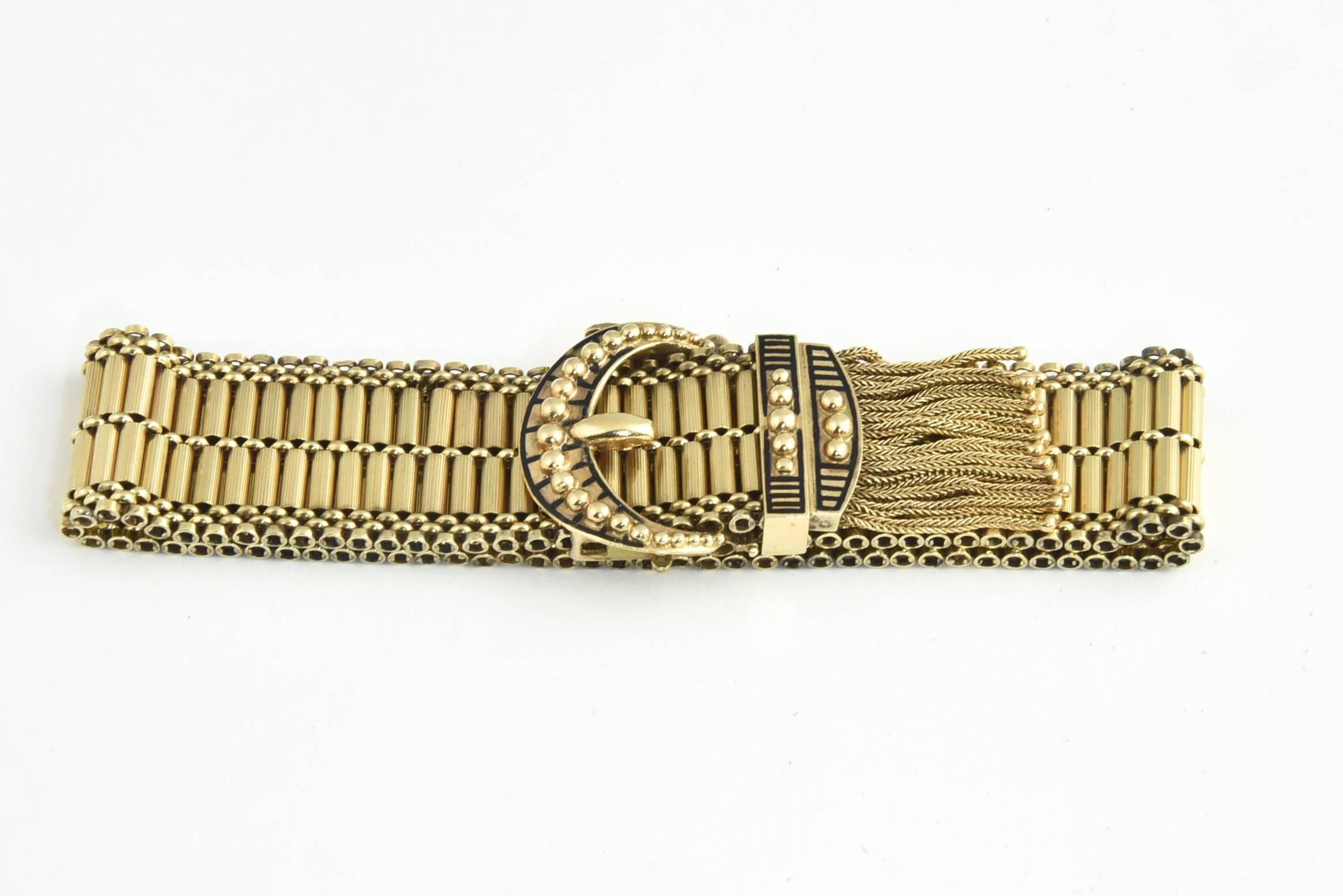 Mid Century Victorian Revival 14k gold bracelet featuring a buckle design accented with black enamel and woven gold tassels that cumulate with a gold ball.

Marked 14k.  This bracelet is extremely adjustable - it's max length would be 9