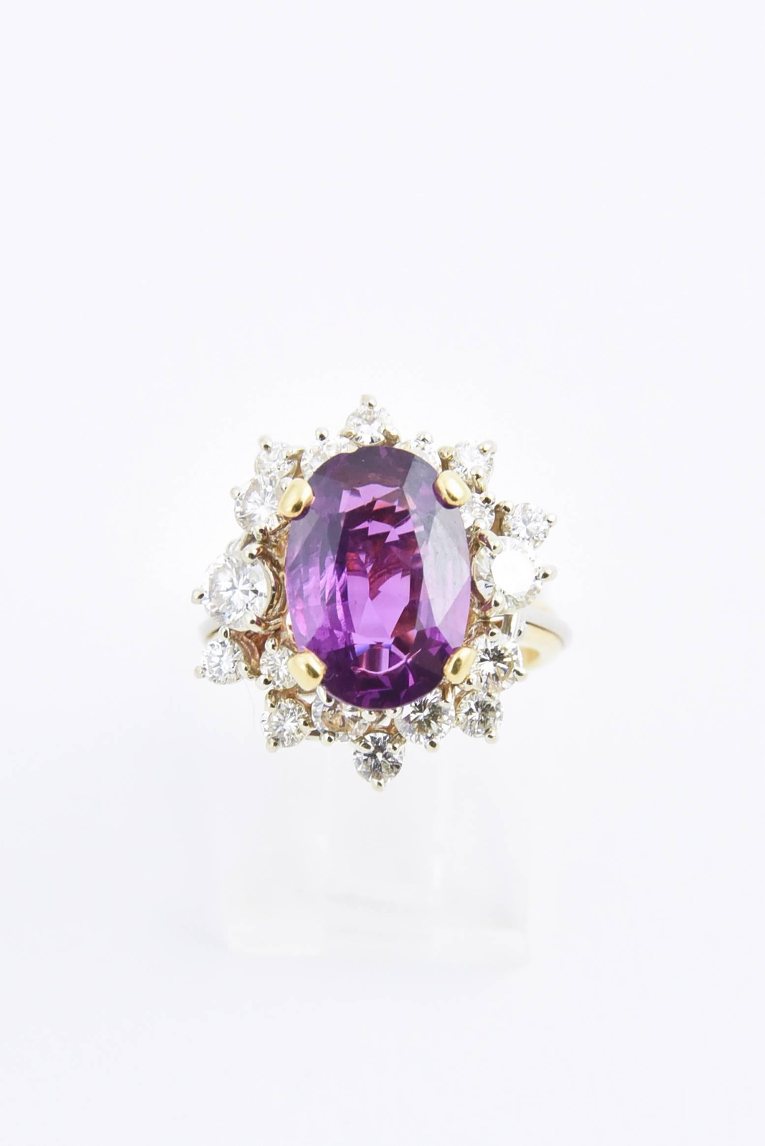 Glamorous sapphire and diamond cluster ring containing an oval pinkish purple sapphire weighing approximately 4 carats set amongst 18 diamonds that weight approximately 1.5 carats. Mounted in a 18k white and yellow gold ring with a scroll design on