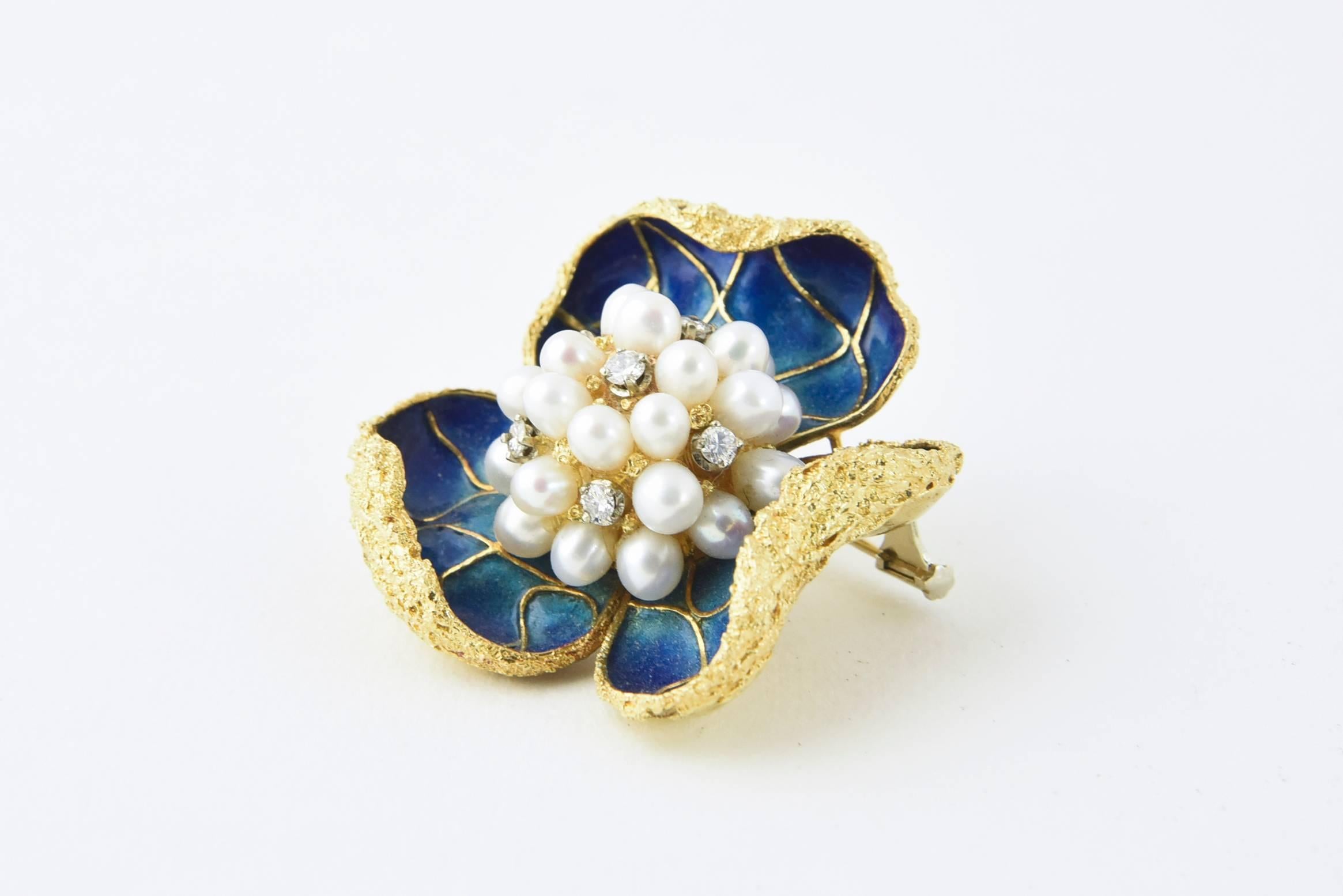 Beautifully made flower brooch with textured petals curling over an intense blue/green/purple enamel flower with a cultured pearl and diamond mounted in 18k yellow gold.