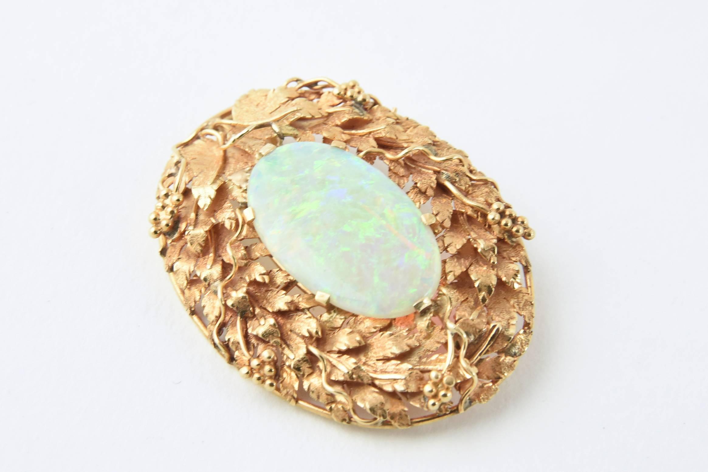 Handmade three dimensional 18k floral design oval brooch pendant constructed to showcase this superb Australian crystal opal (approximately 16mm X 27mm).  The opal has broad flashes of reds, greens, blues and yellows.  The 18k gold frame shows