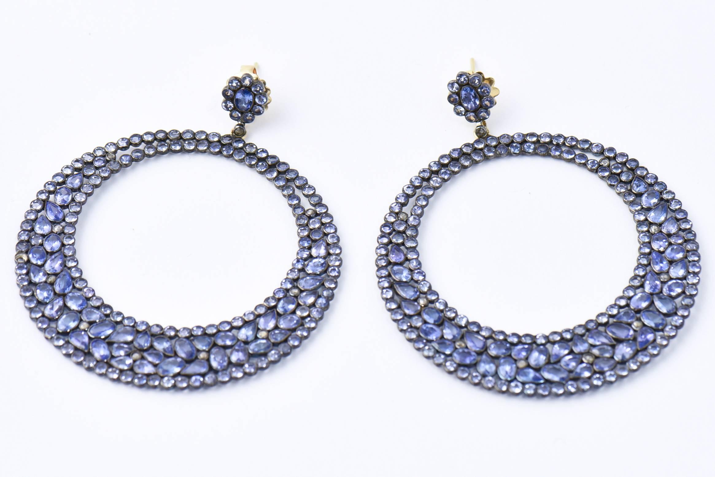 Lovely long dangling earrings that resemble a stained glass window. An tanzanite flower is set through the ear with an 18k yellow gold post and back. The large open round drop features 28 carats of see through tanzanite and .45 carats of diamonds