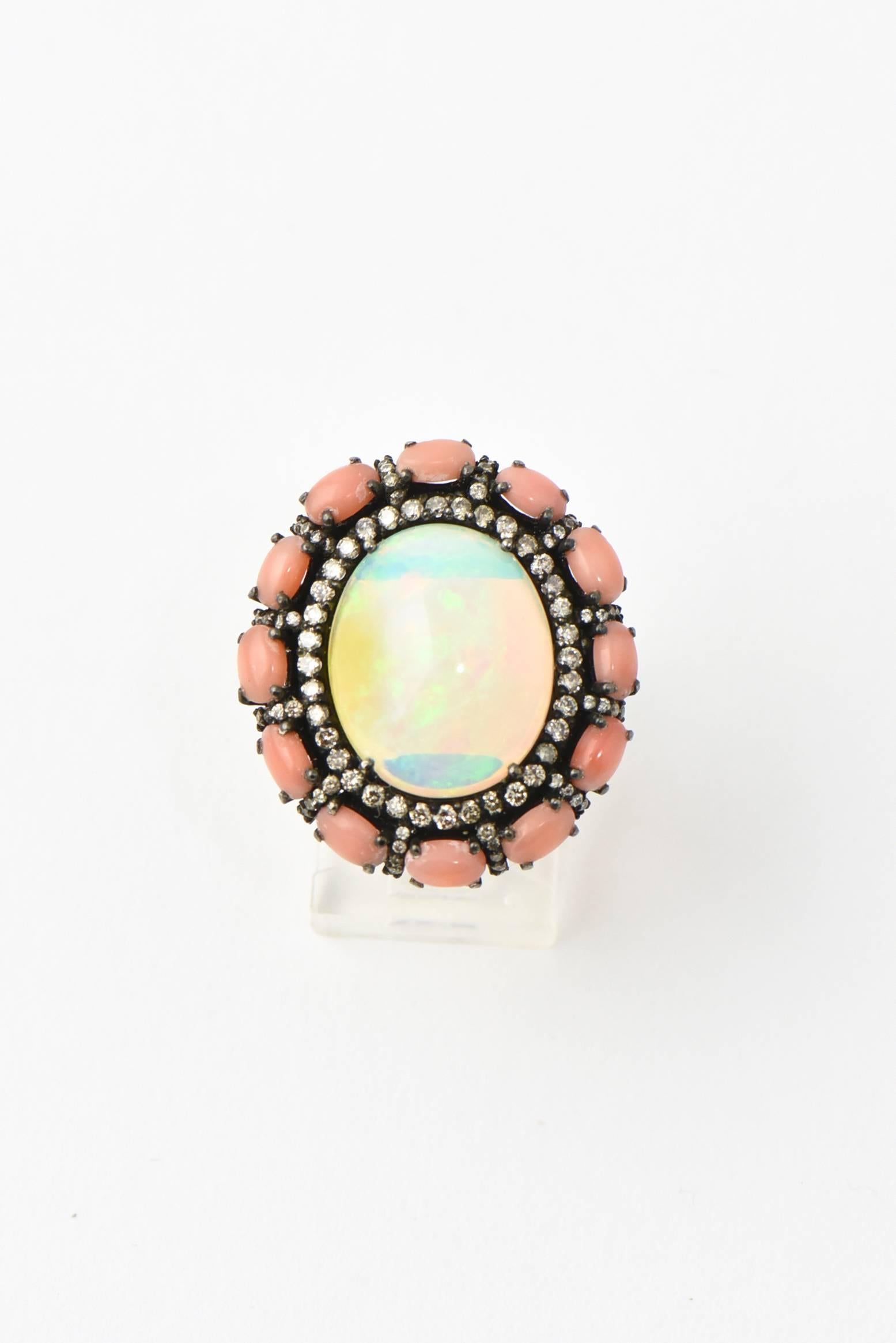 Striking cocktail ring featuring a wonderful combination of a cabochon oval crystal opal within a blacked sterling silver frame of diamond.  Outside the diamond frame is another from of coral oval beads separated brows of diamonds.  The ring is a