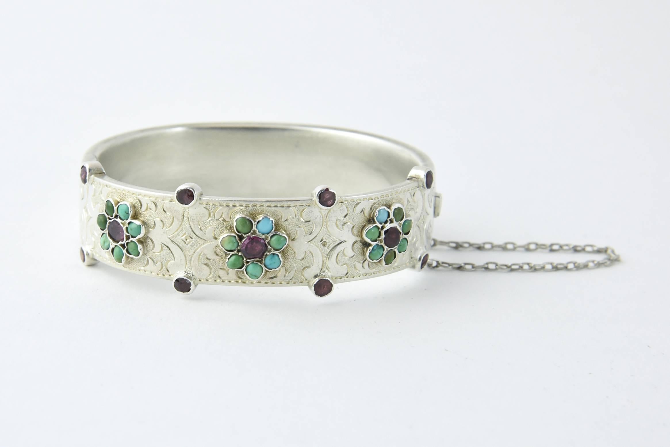 Finely made Austro Hungarian Empire Bangle Circa 1872-1921 
This exquisitely made bangle silver etched bangle has three bezel set turquoise flowers with ruby centers.  The bangle edge is accented with four additional  with bezel set rubies on each