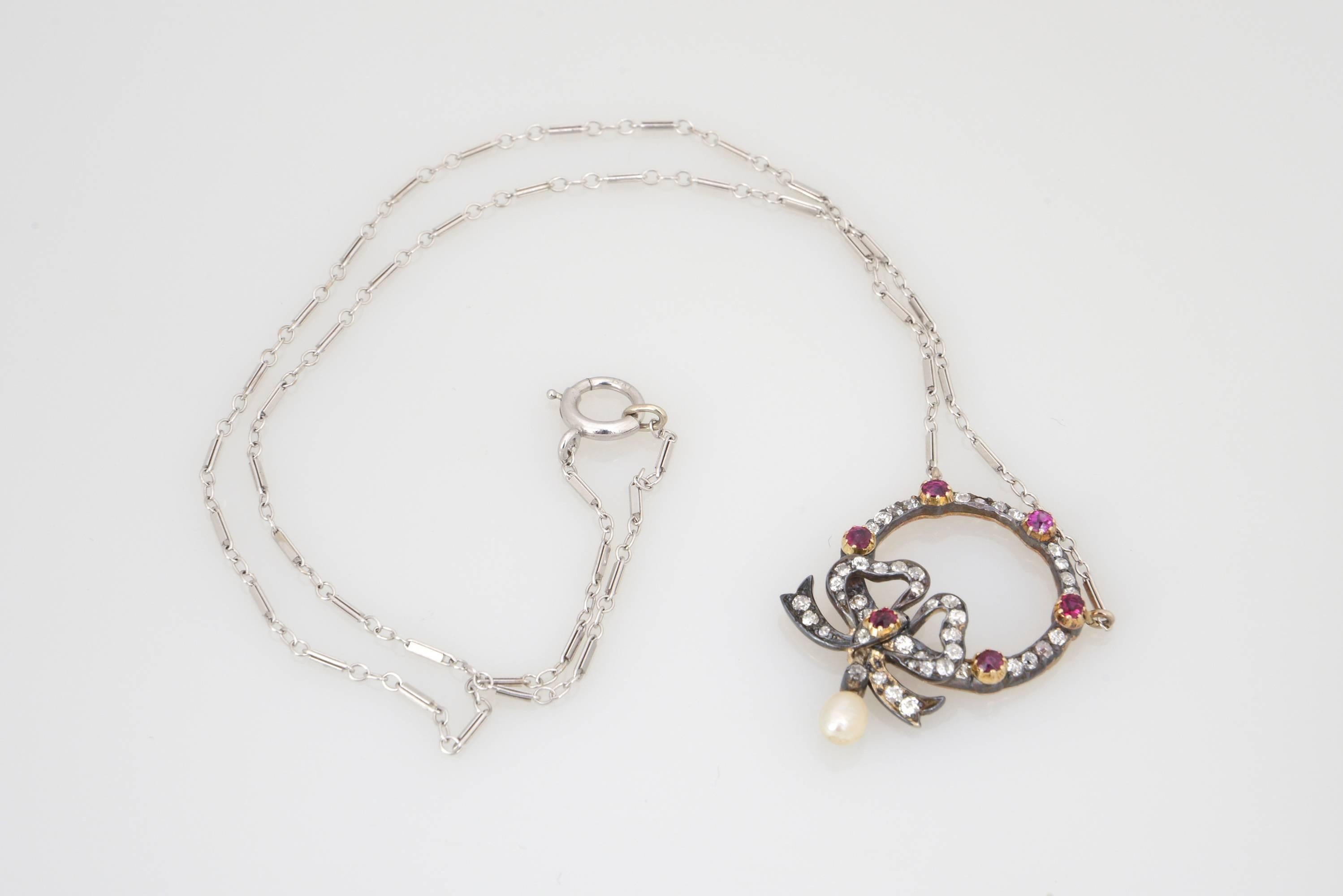 A rare and delicately crafted antique turn of the century Edwardian Belle Époque necklace pendant with an emblematic for that period bow design. The pendant is made of silver on gold with the gems set in silver. Finished with a very nice and fine