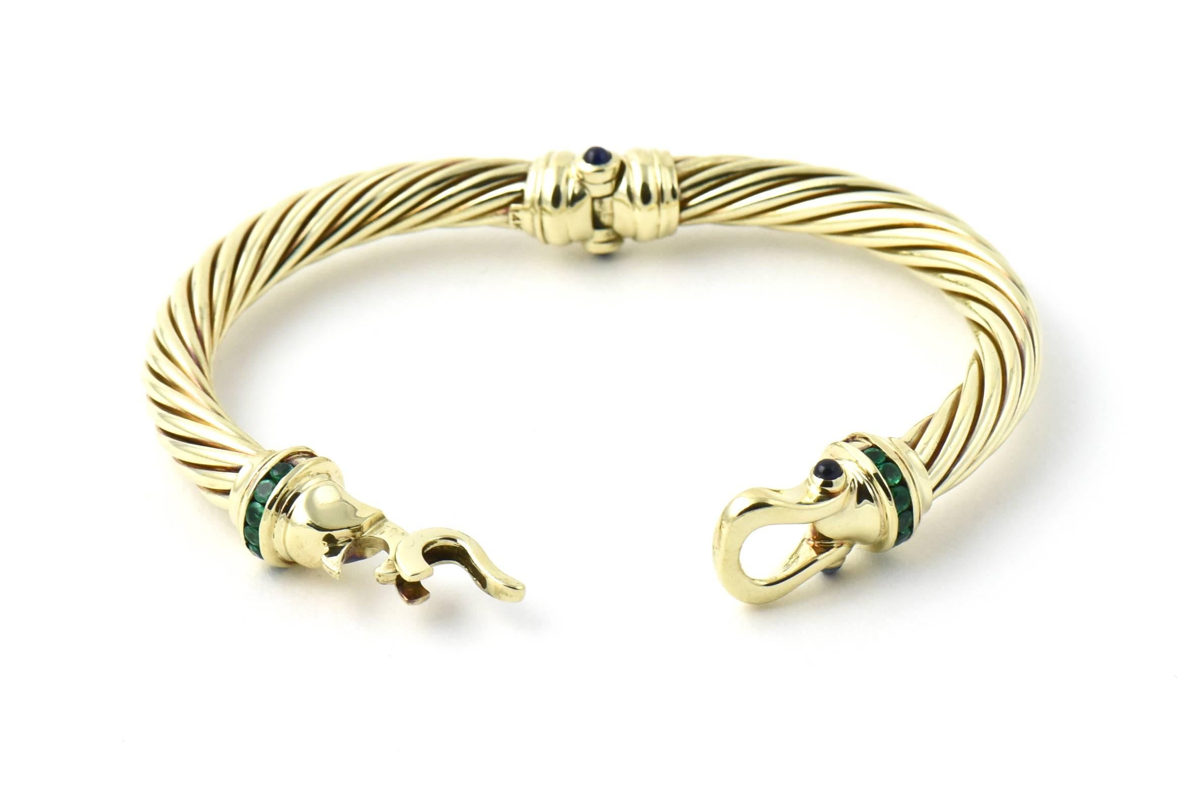 David Yurman Cable Classic Buckle Bracelet with line of channel set emeralds on either side of the hook and buckle and four cabochon sapphires set in an 14k yellow gold bangle bracelet.  The cable area is 6.8mm wide.  Inner area circumference