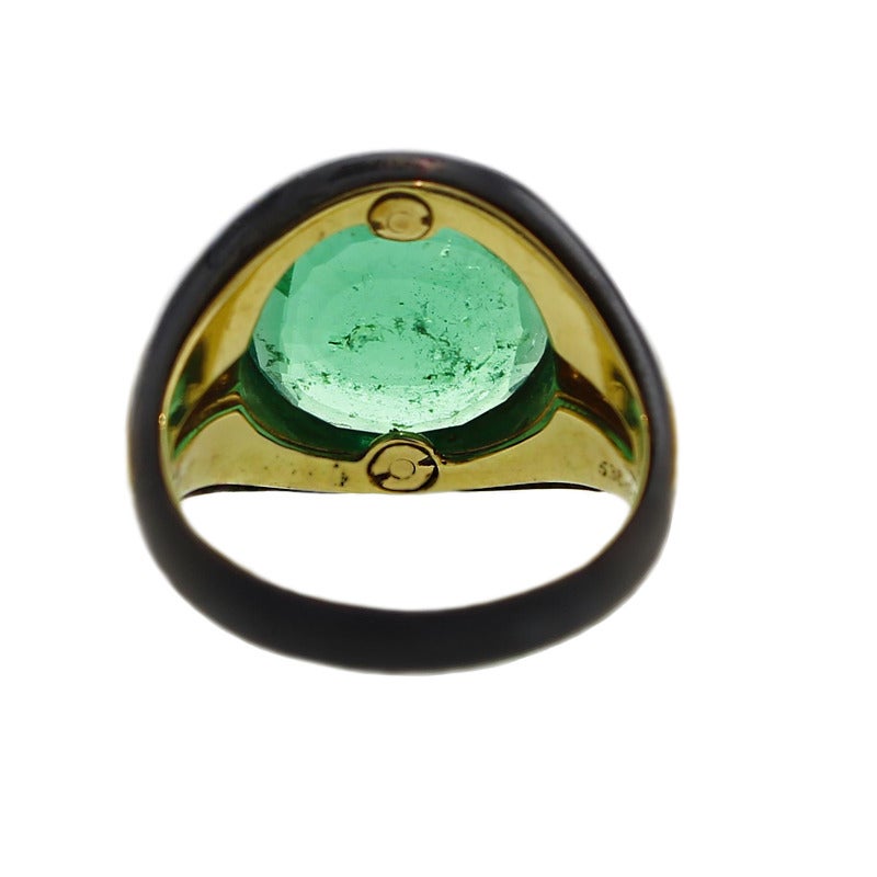 Circular-cut Colombian emerald 5.38 carats, collet-set to the blackened mount, with tapering channel-set square-cut diamond shoulders and yellow gold. Finger Size P. Signed Bulgari 1980s. With SSEF certificate.