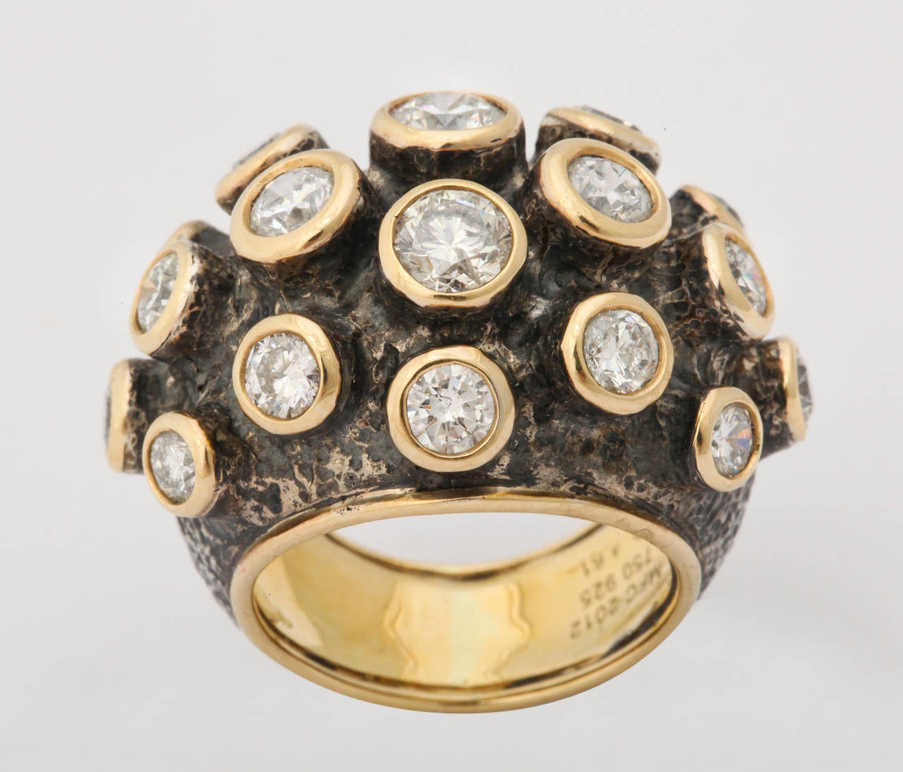 A bold design by Marilyn Cooperman featuring 4.61cts of round, white diamonds.  Each stone is individually bezel set in 18kt yellow gold and these bezels are in turn mounted on the patinated silver and 18kt gold ring.  One of a kind, size