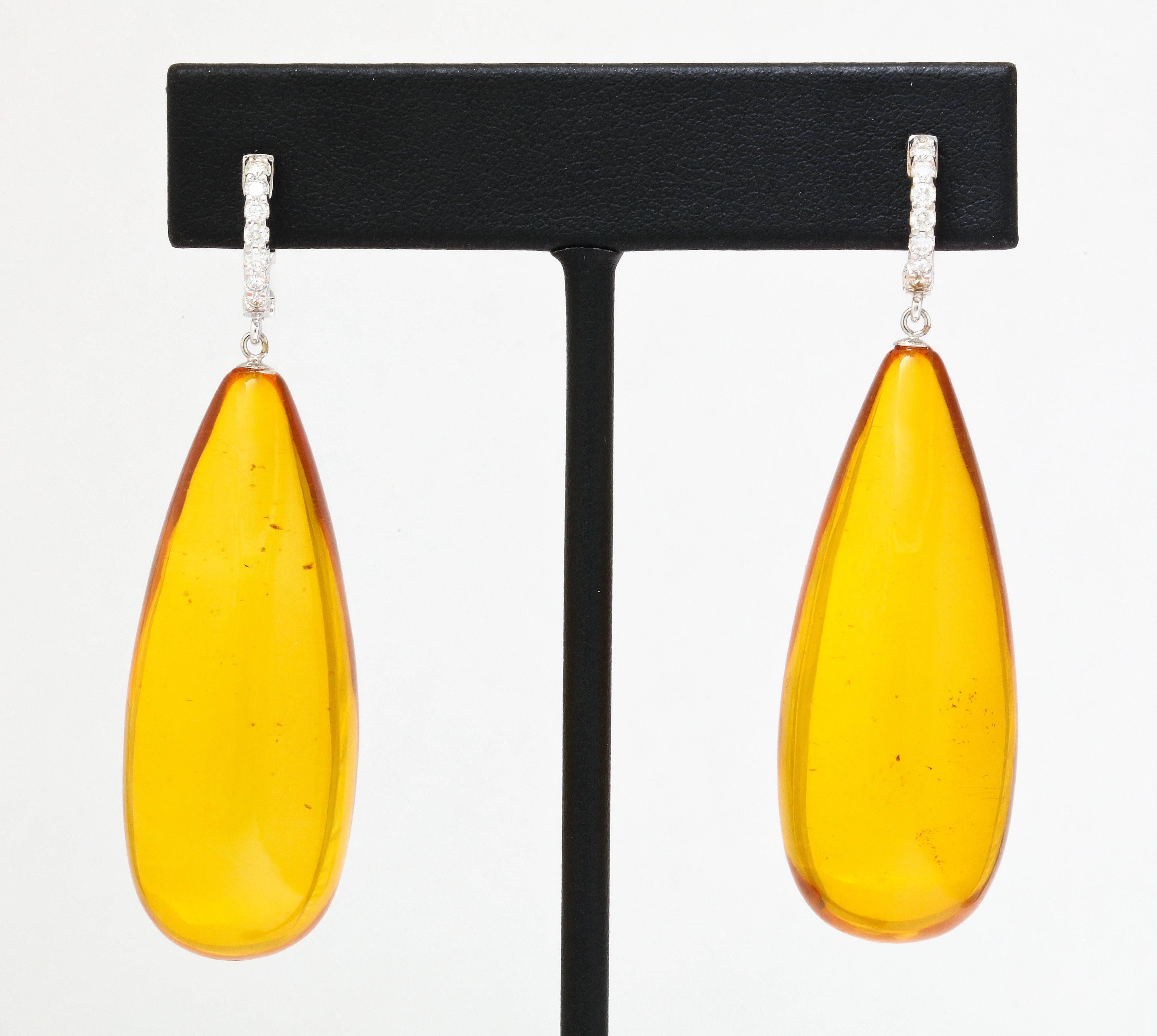 An impressive pair of 45.5x18mm rich, cognac colored amber drops are suspended from diamond hoops.  The result is a bold and colorful look that is a pleasure to wear due the the feather light weight of amber.  While used in jewelry  the same way as