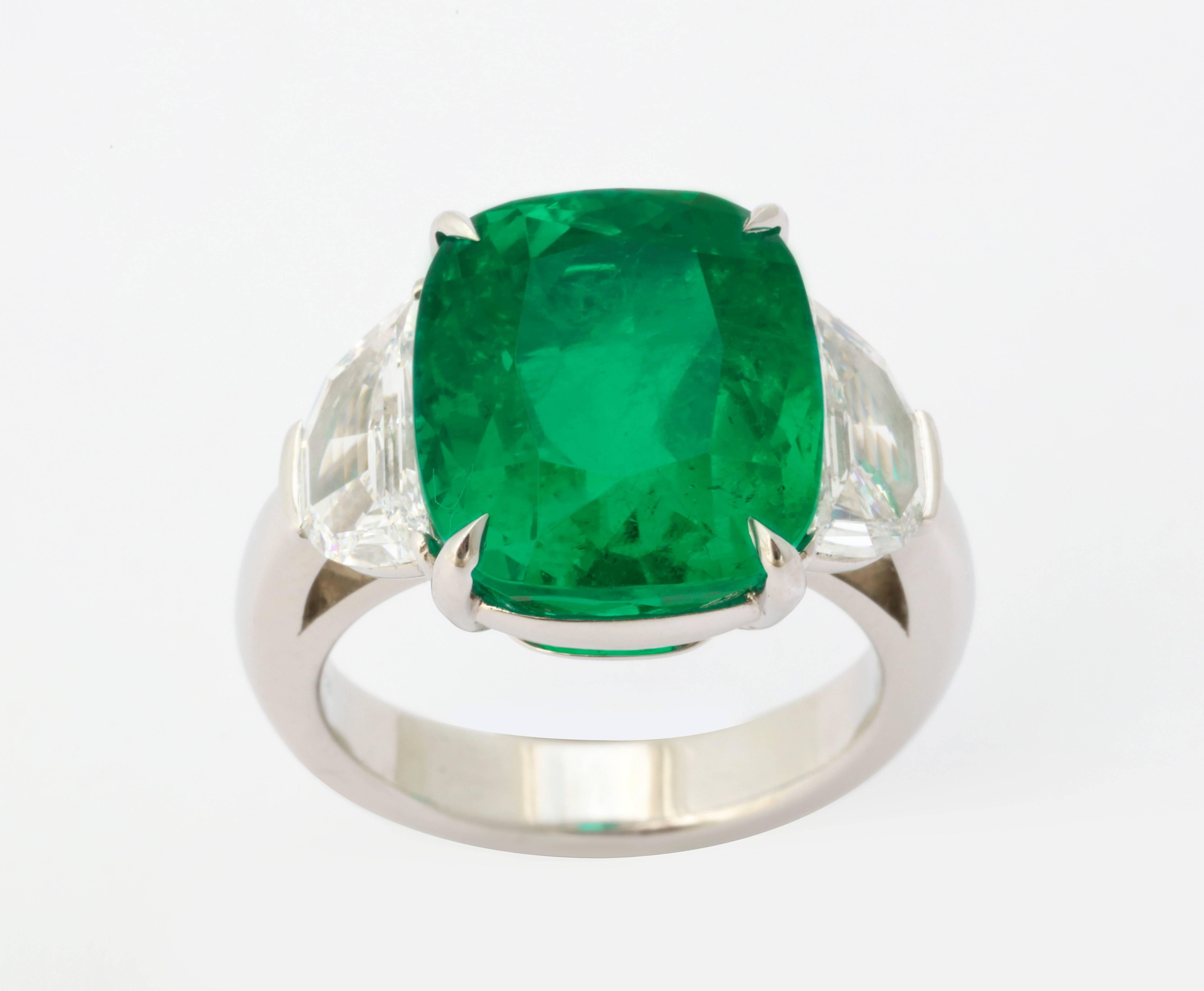 The perfectly cut cushion shape emerald weighs 9.15 carats and is exquisitely set in platinum, flanked by a pair of half moon diamonds weighing over 1 carat each (2=2.15cts total weight).  The gemological certificate is from the highly esteemed