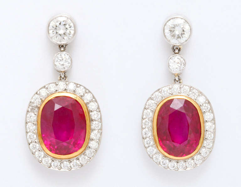 These classic earrings feature a perfectly matched, fine pair of bright red oval rubies delicately surrounded with diamonds.  The rubies measure 9.5x7.5mm and weigh 4.80cts for the pair.  The diamond mountings are set with 2 stones weighing a total