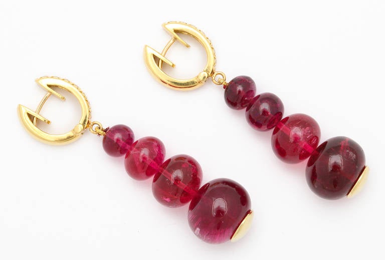 Four delicious red rubelite beads hang from each earring like bright red gumdrops.  The tops are set with white diamonds in 18kt yellow gold.  8 rubelite beads weigh 73.54cts and 14 round diamonds weigh 0.39cts in total.  For pierced ears.

From a