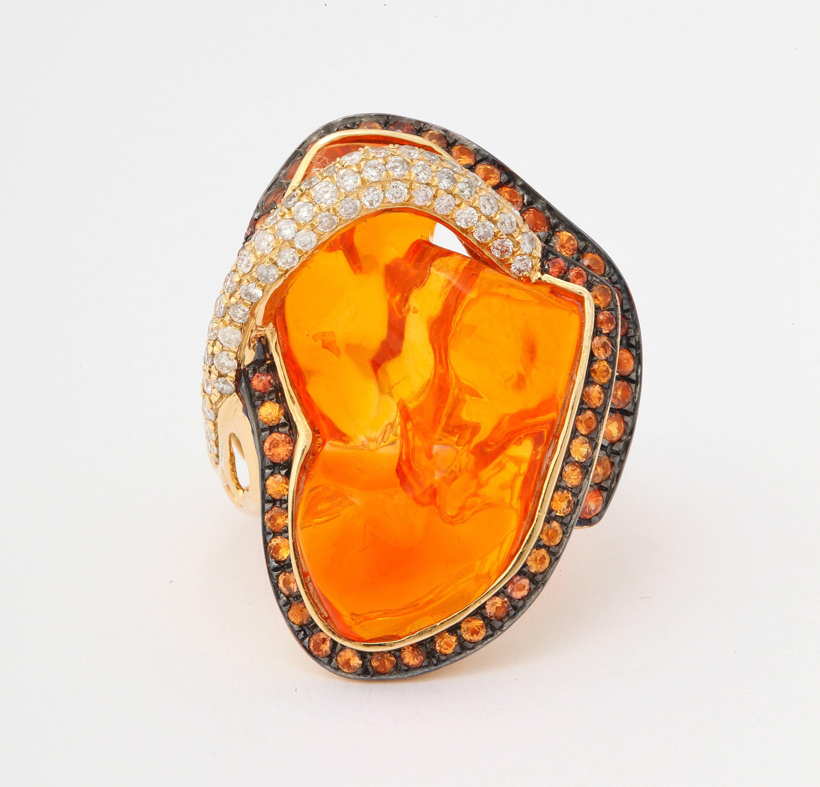 The ring features a centrally set fee form, bright orange Mexican opal.  Set in blackened gold are equally bright orange sapphires, while the white diamonds are set into yellow gold.  Bold, unique and original, this piece is one of a kind.

For