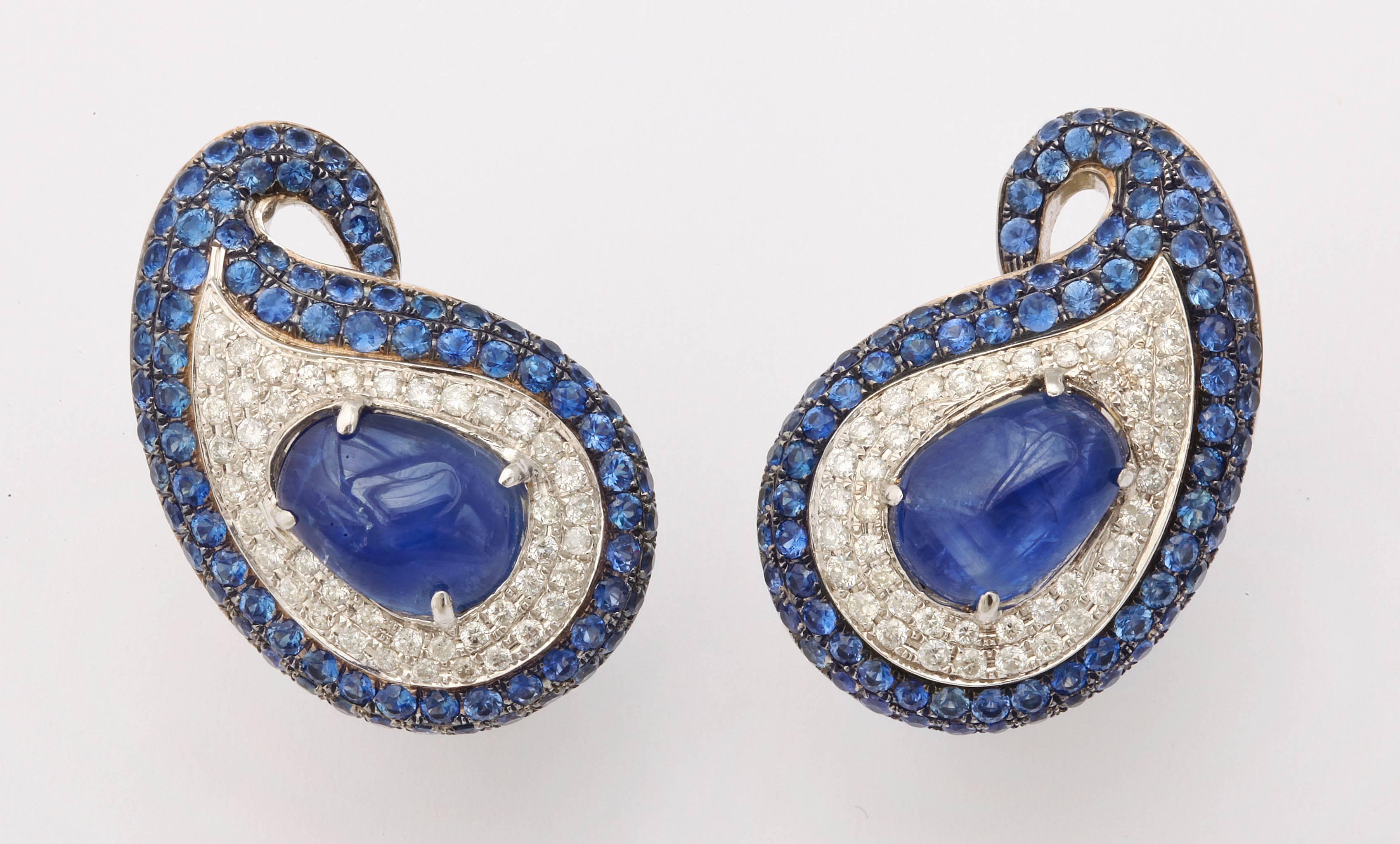 These stylish earclips feature two different forms of blue sapphire to create this bold look.  The central cabochons are a soft royal blue while the faceted sapphires are vibrantly brilliant.  Further accented with white diamonds they can be worn