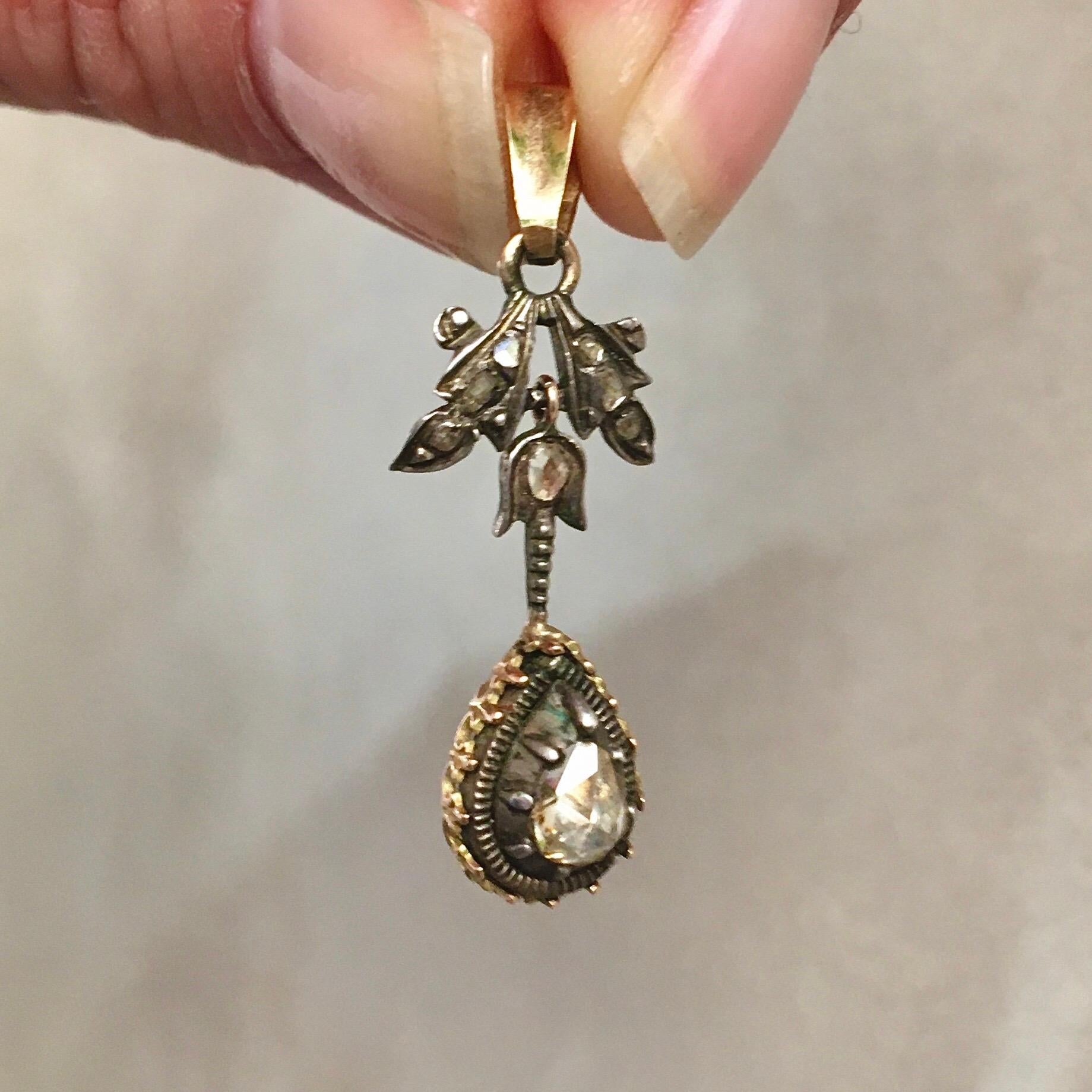 A Victorian 14 karat gold and silver pendant set with rose cut diamonds. The pendant has a beautiful design and an entourage of rose cut diamonds set in a gold and silver setting. The border is decorated with 14 karat gold and the center is made of