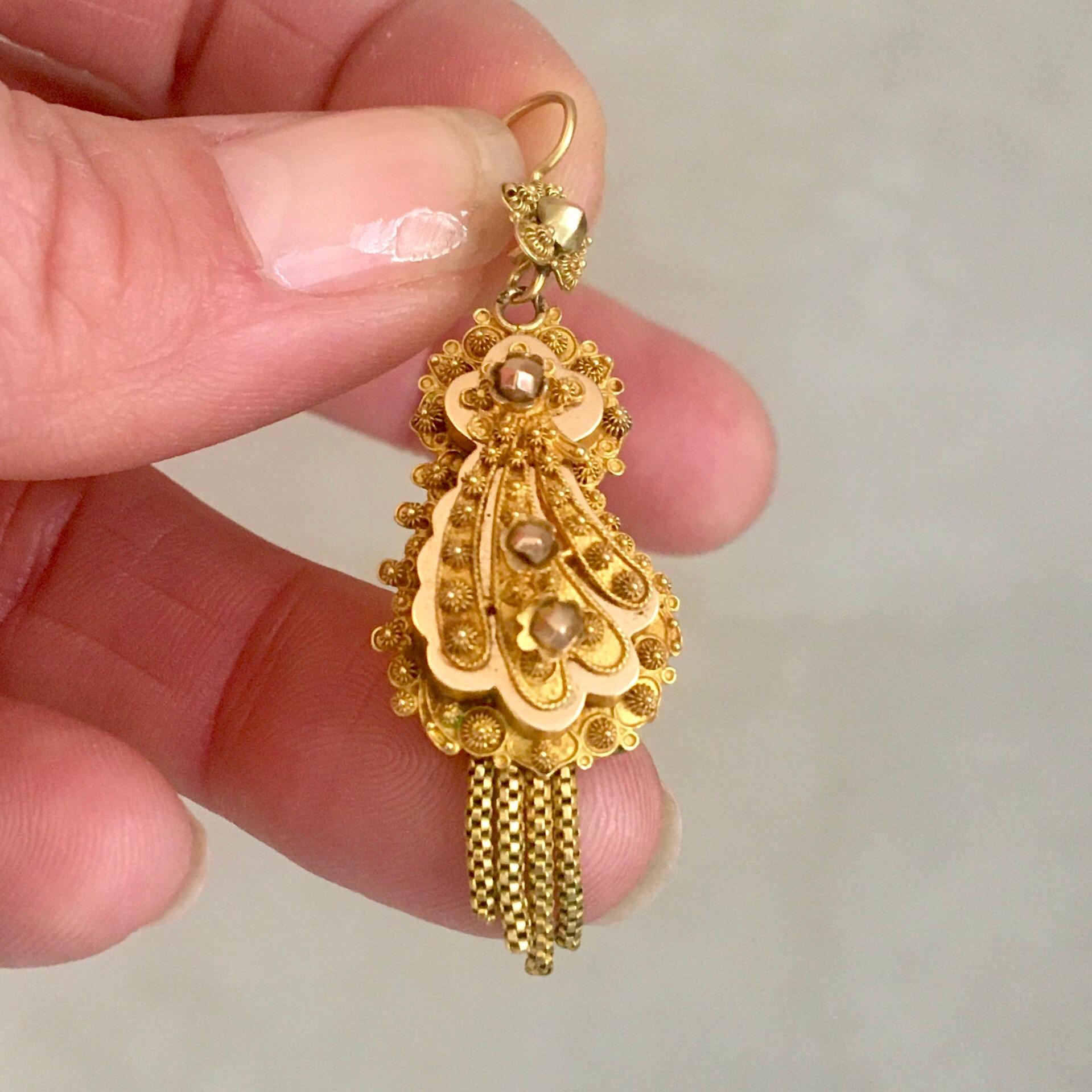 An antique 19th century 14 karat yellow gold pendant with a fantasy design of fine cannetille work. The center of the pendant has a raised edge, which is decorated with cannetille and gold ornaments. Below the top four gold tassels are swing freely.