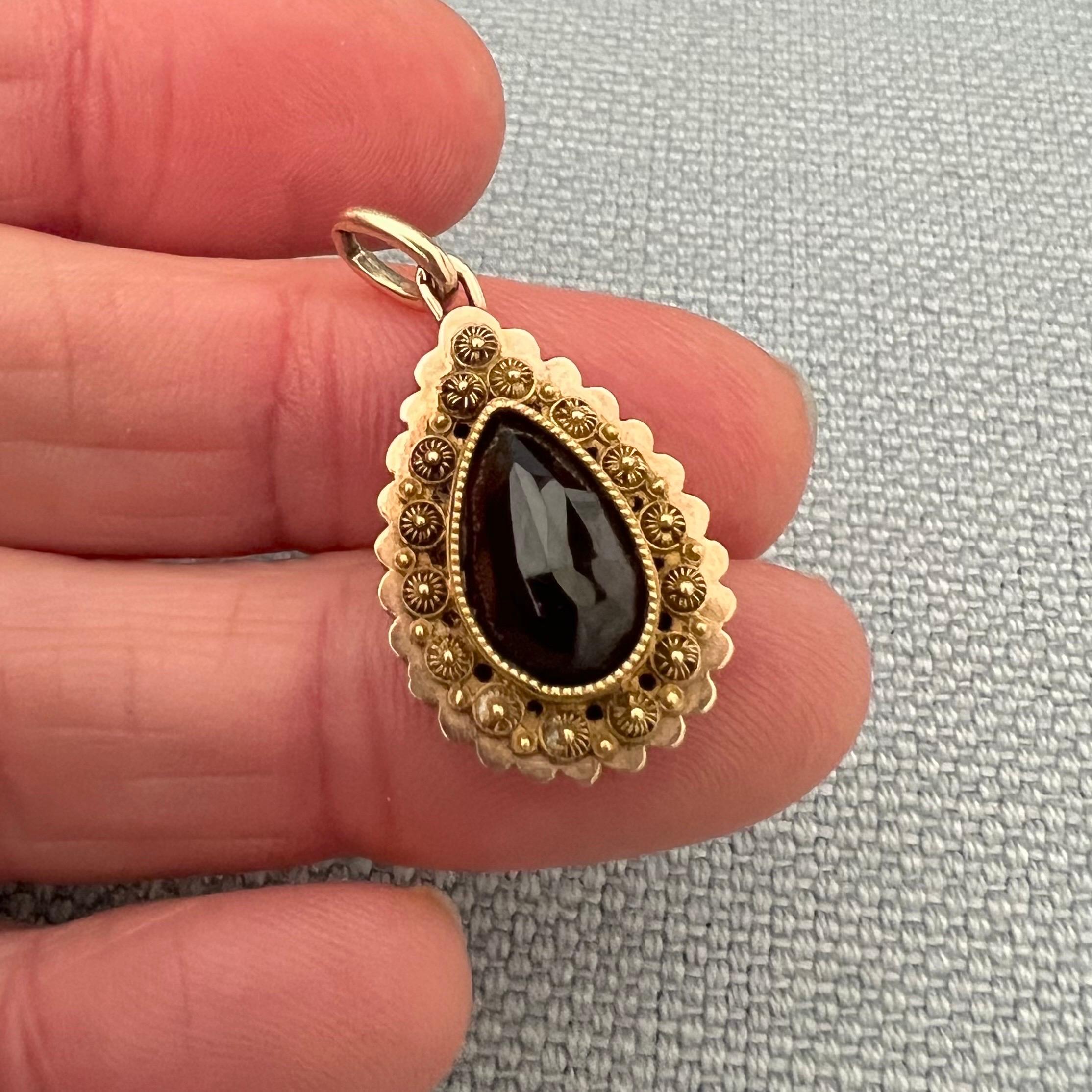 A n antique 9th century gold cannetille work pendant set with a drop shaped faceted garnet stone. The cannetille work is delicately made by hand. In the Netherlands they also call these rosettes 'spiders', there is the spiders body in the center