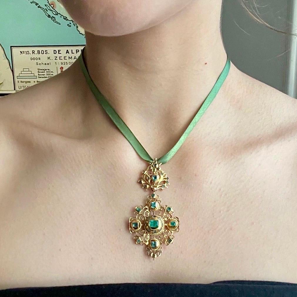 A magnificent antique 18th century gold and emerald Iberian pendant. This pendant is truly a piece of history and made in Cordoba, during the late 18th century. This gorgeous jewel encrusted with 34 individual table cut Colombian emerald stones