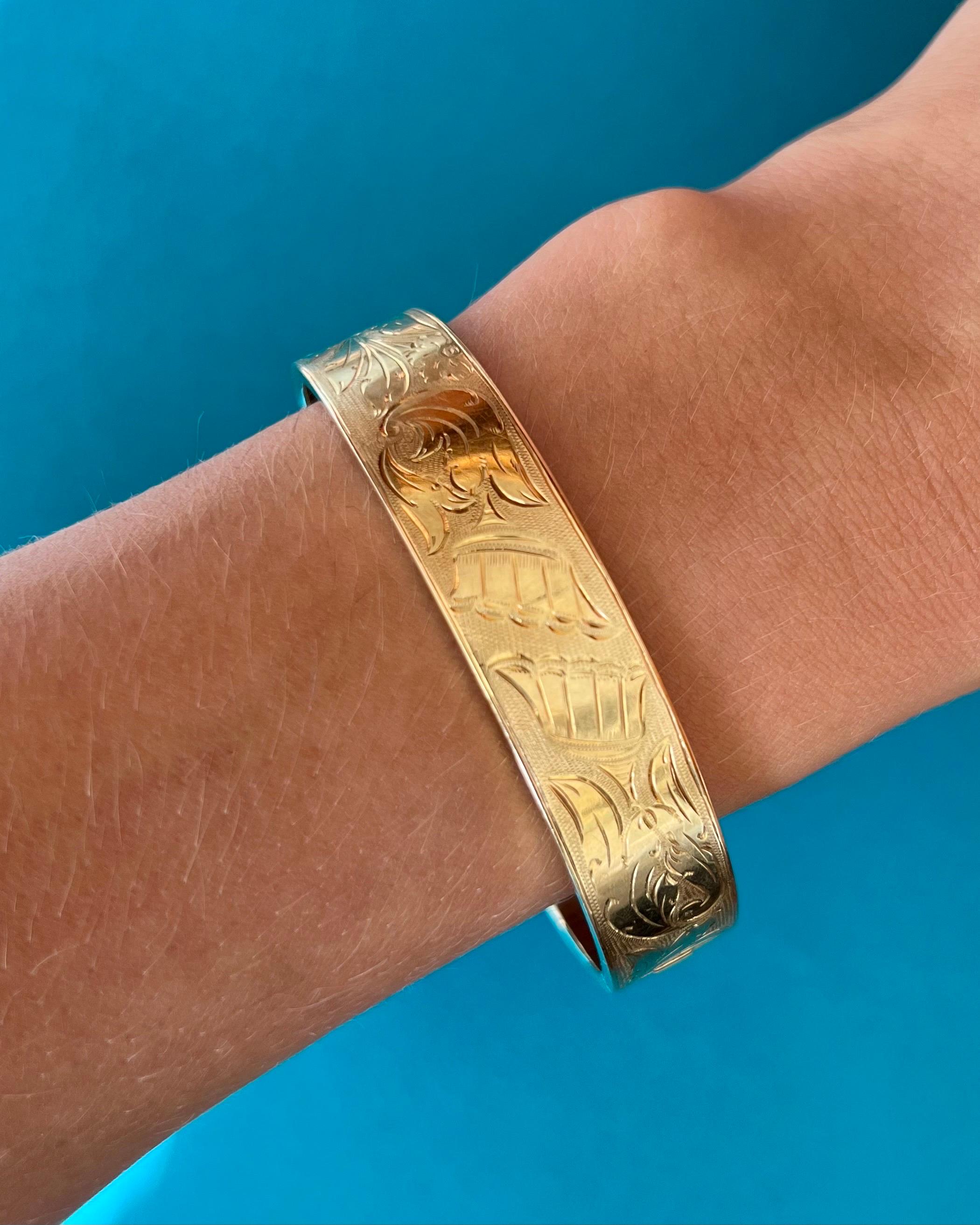 A beautiful 14 karat yellow gold bangle bracelet designed with nice floral engravings. The bracelet is detailed with scrolling leaves and a flower pattern, which covers the front of this bracelet and has a matted satin finish. The back side of the