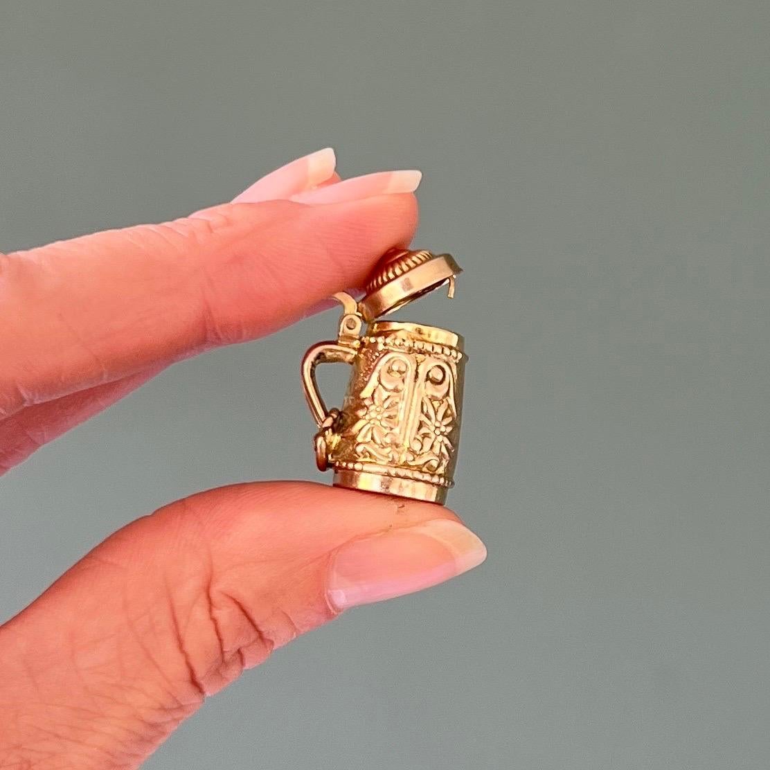 Il s'agit d'un pendentif vintage en or jaune 9 carats représentant une chope de bière. Ce stein de bière vintage présente de superbes détails avec un magnifique décor floral d'edelweiss sur l'ensemble du stein de bière. Le couvercle du mug peut être