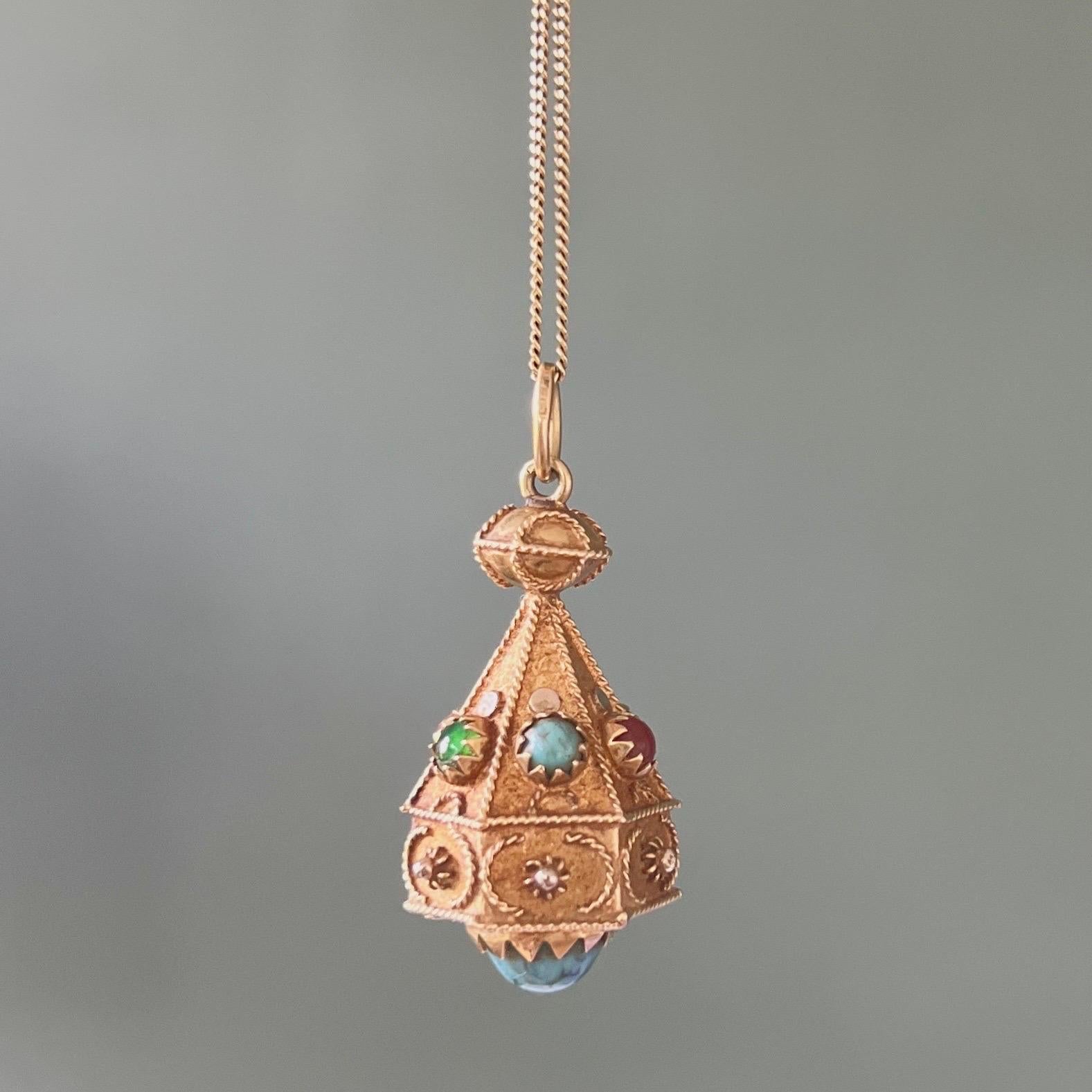 An attractive Etruscan Revival 14 karat gold cannetille charm pendant. This pendant is decorated with cannetille and set with various colored cabochon cut gemstones. Smaller stones are set on the six angular sides, including turquoise, carnelian and