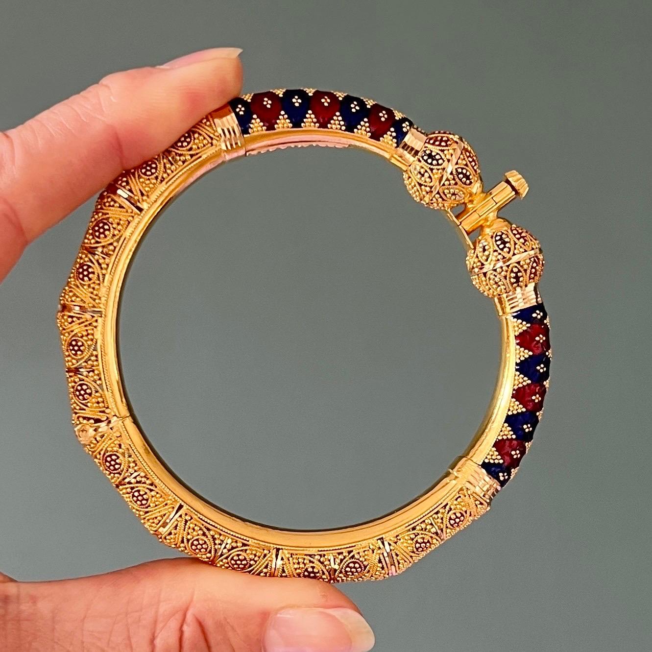 An ornate 20 karat yellow gold filigree enameled bangle bracelet. The gold of the bracelet is richly decorated with very fine filigree work and granulation. Next to the closure, the bangle is set with two filigree balls and counterparts of enameled