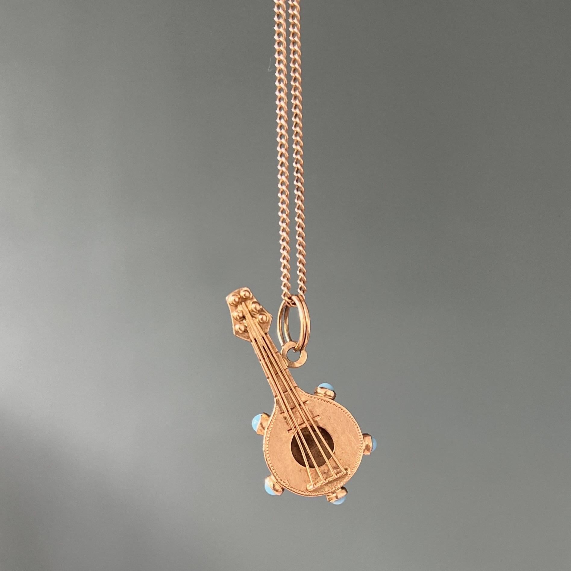 A vintage 18 karat yellow gold mandoline guitar charm pendant. The guitar is nicely crafted and set with five turquoise stones around the body. The mandoline is detailed with four strings and tuners at the top. I can already hear some nice sounds