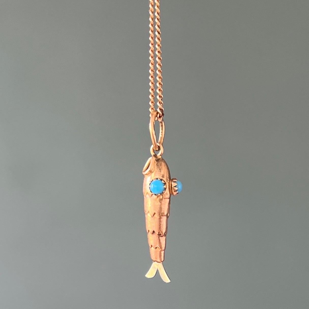 An 18 karat yellow gold vintage fish charm pendant. The fish is lovely and nicely created with turquoise stone eyes, the body is detailed with carving and raised work which resembles the scaly skin. The tail is fashioned in silver and the body of