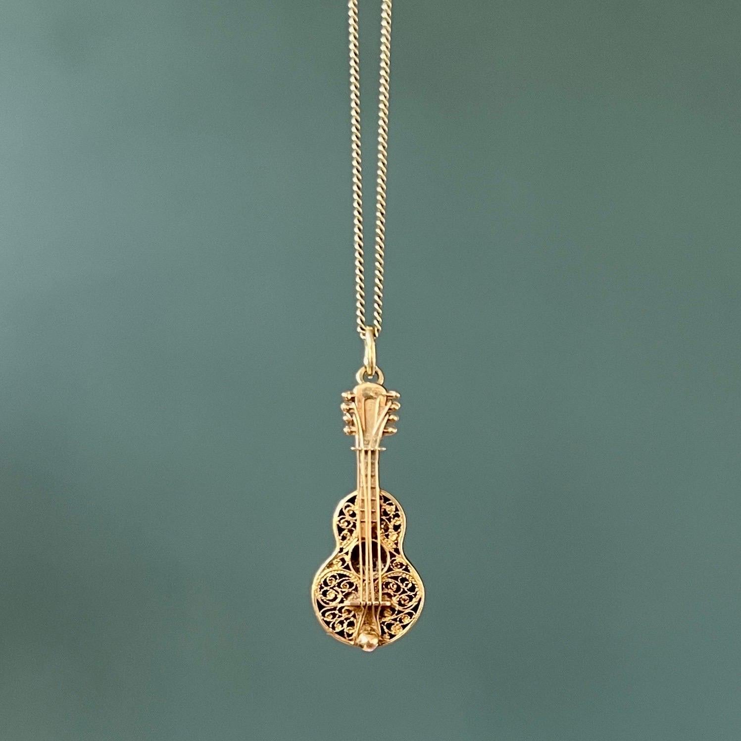 A vintage 1960's 14 karat gold guitar charm pendant. The top of the guitar is stylized with fine filigree and gold strings. The head of the guitar is equipped with tuning pegs.  

Collect your own charms as wearable memories, it has a symbolic and