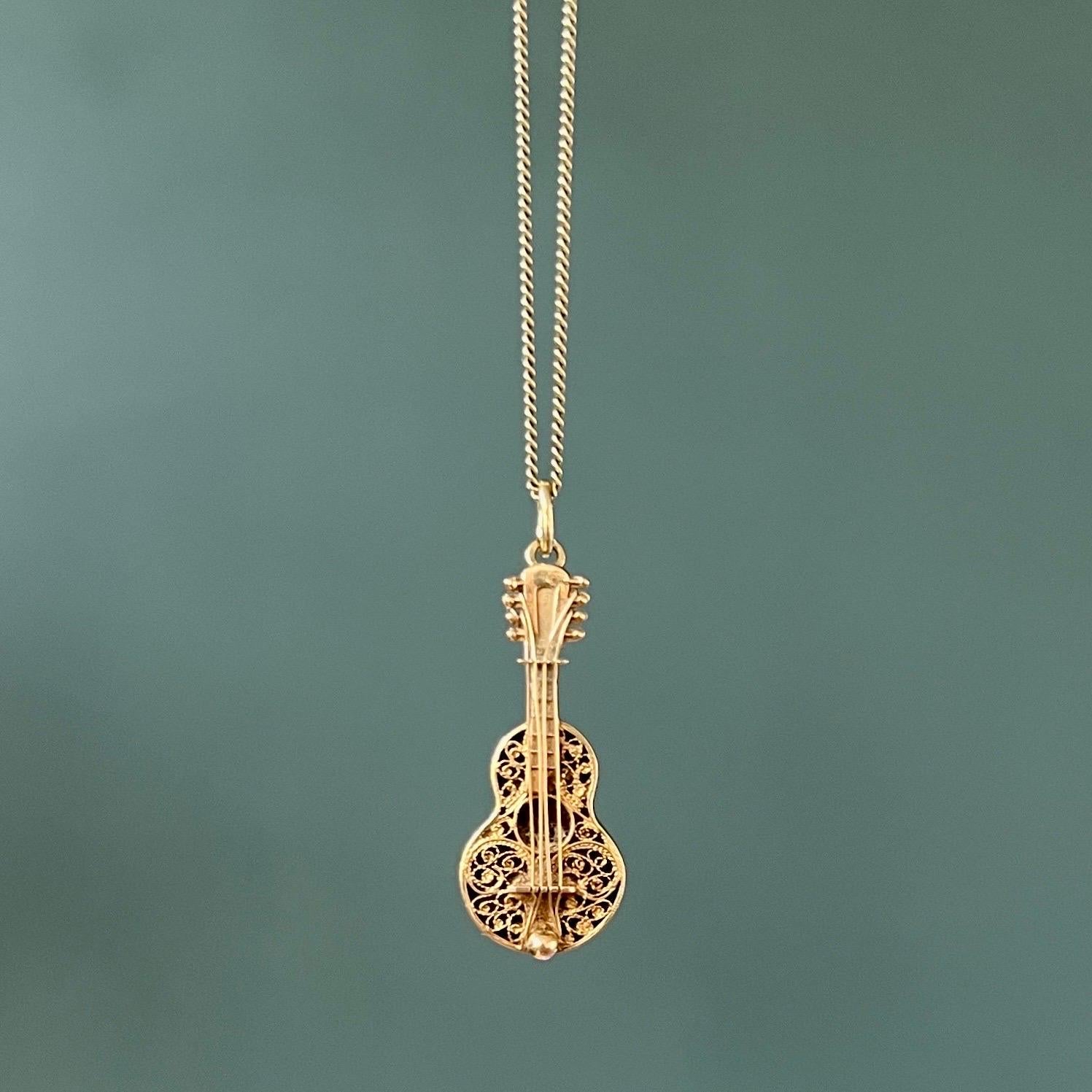 Pendentif en or 14 carats avec breloque en forme de guitare, datant des années 1960. La table de la guitare est stylisée avec de fins filigranes et des cordes en or. La tête de la guitare est équipée de chevilles d'accordage.  

Collectionnez vos