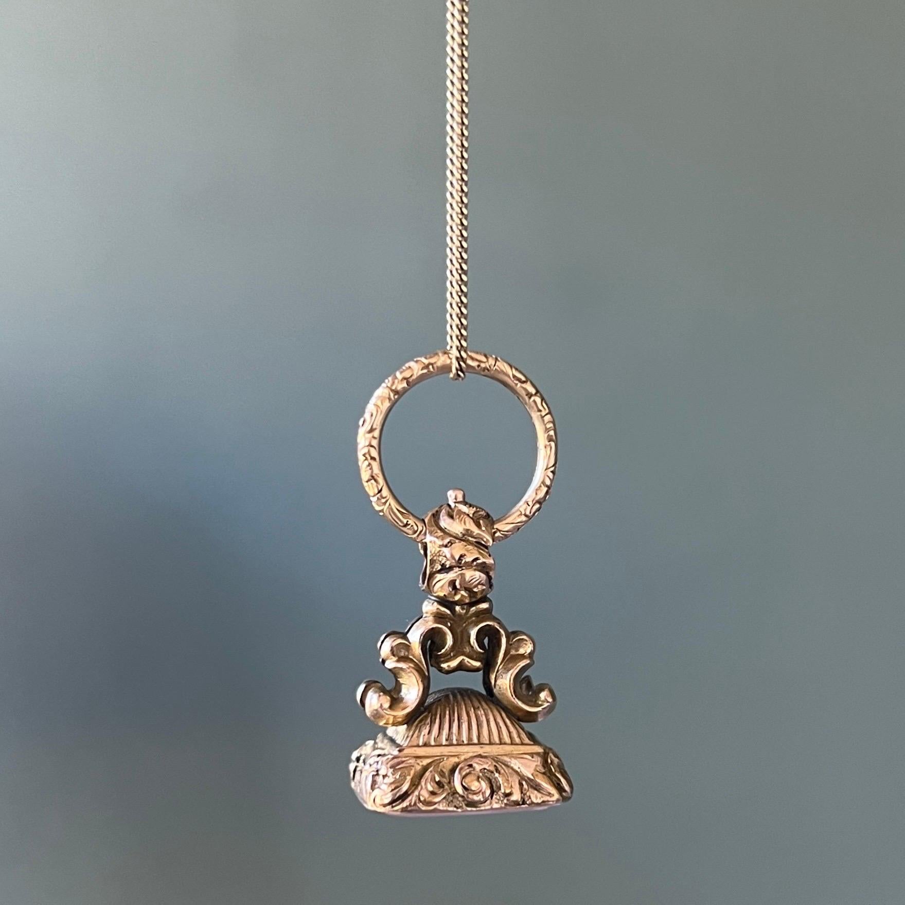 An antique early Victorian 9 karat gold seal fob pendant. This gorgeous seal fob with typical scrolling arches leading to an integral bail attached to a gold split ring. The split ring is embellished with deeply carved patterns of floral and foliate