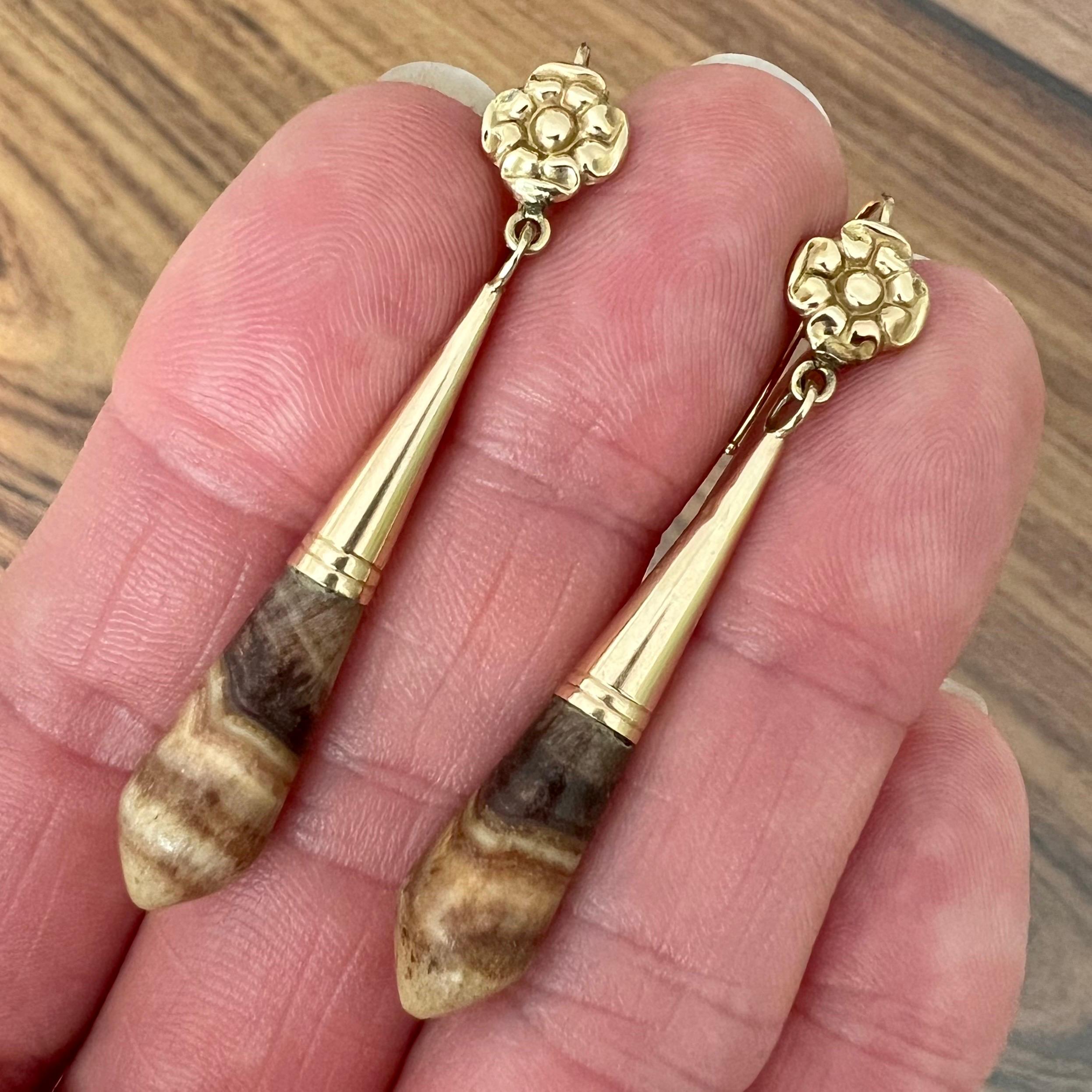 A pair of antique gold dangle earrings made with petrified wood. These drop-shaped papules are set in 14 karat gold caps and dangling under a Tudor rose flower. It is a beautiful balance between nature - the warm glow of the gold and the organic