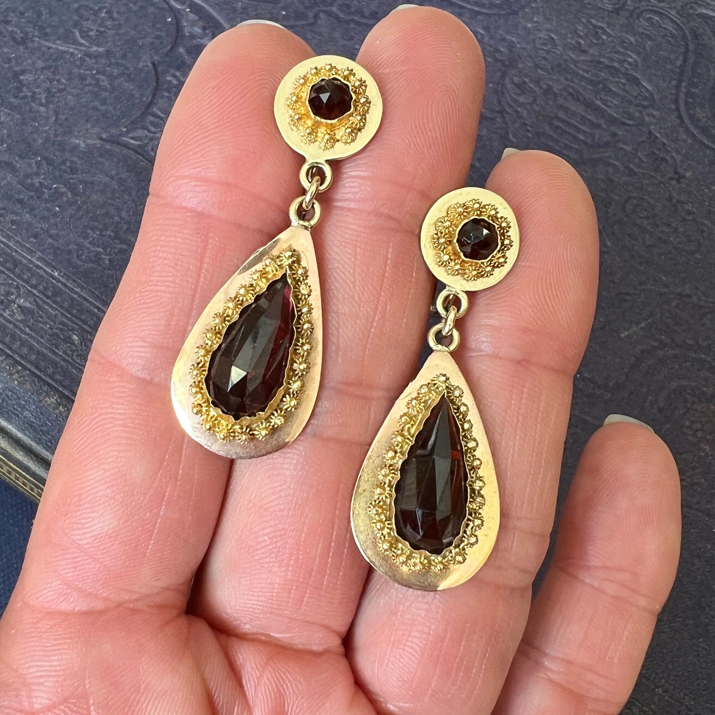 Garnets, the birthstone of January, are beautifully set in these 19th century dangle earrings. The earrings are made with fine cannetille and garnet stones set in a 10 karat gold mounting. The earrings have a rosette earpiece with a drop-shaped