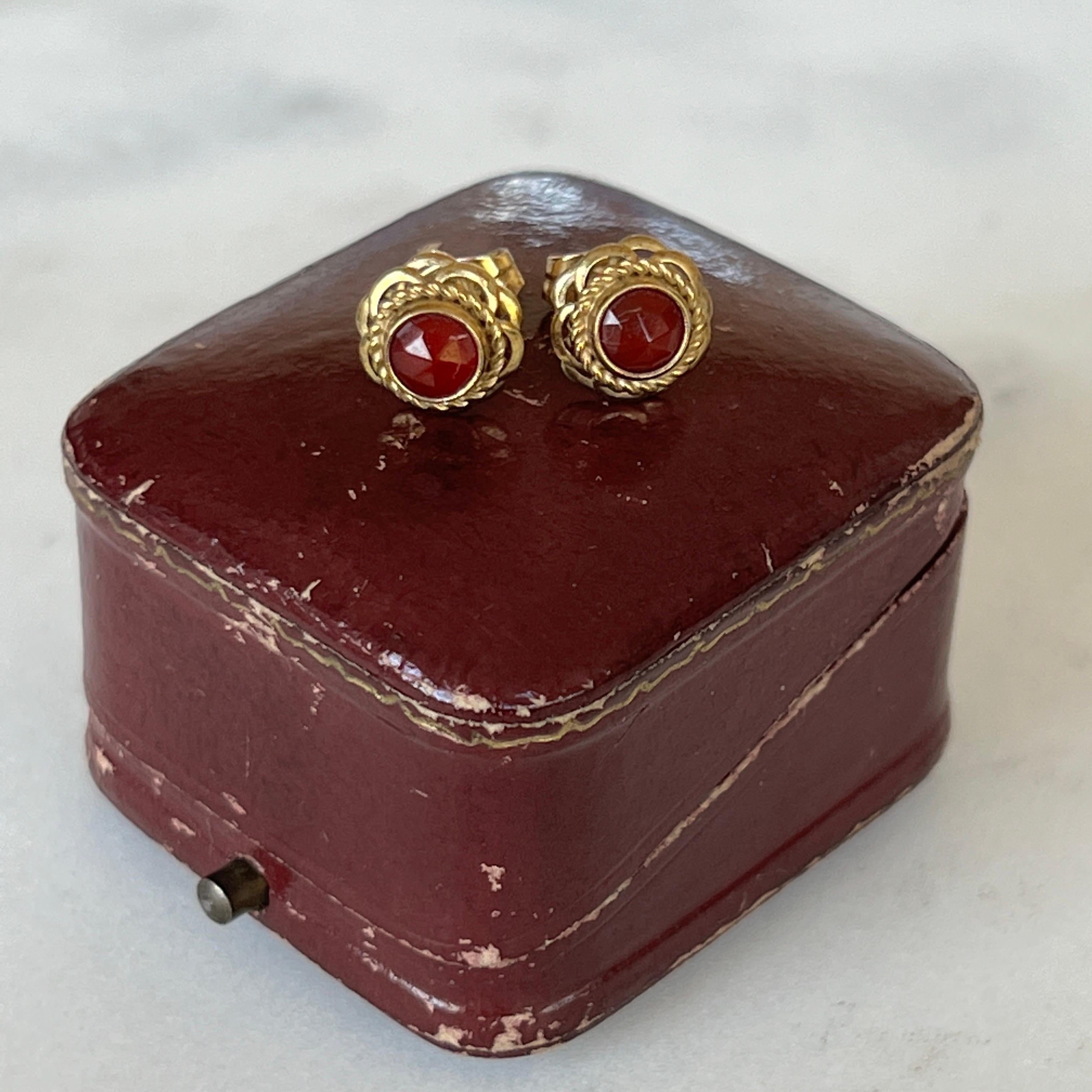 An antique pair of elegant natural carnelian stud earrings from Late 19th Century. The faceted carnelian is set in a lovely embellished 14 karat gold mounting. The beautiful stone is surrounded by a fine gold rope motif and the edge is made with a