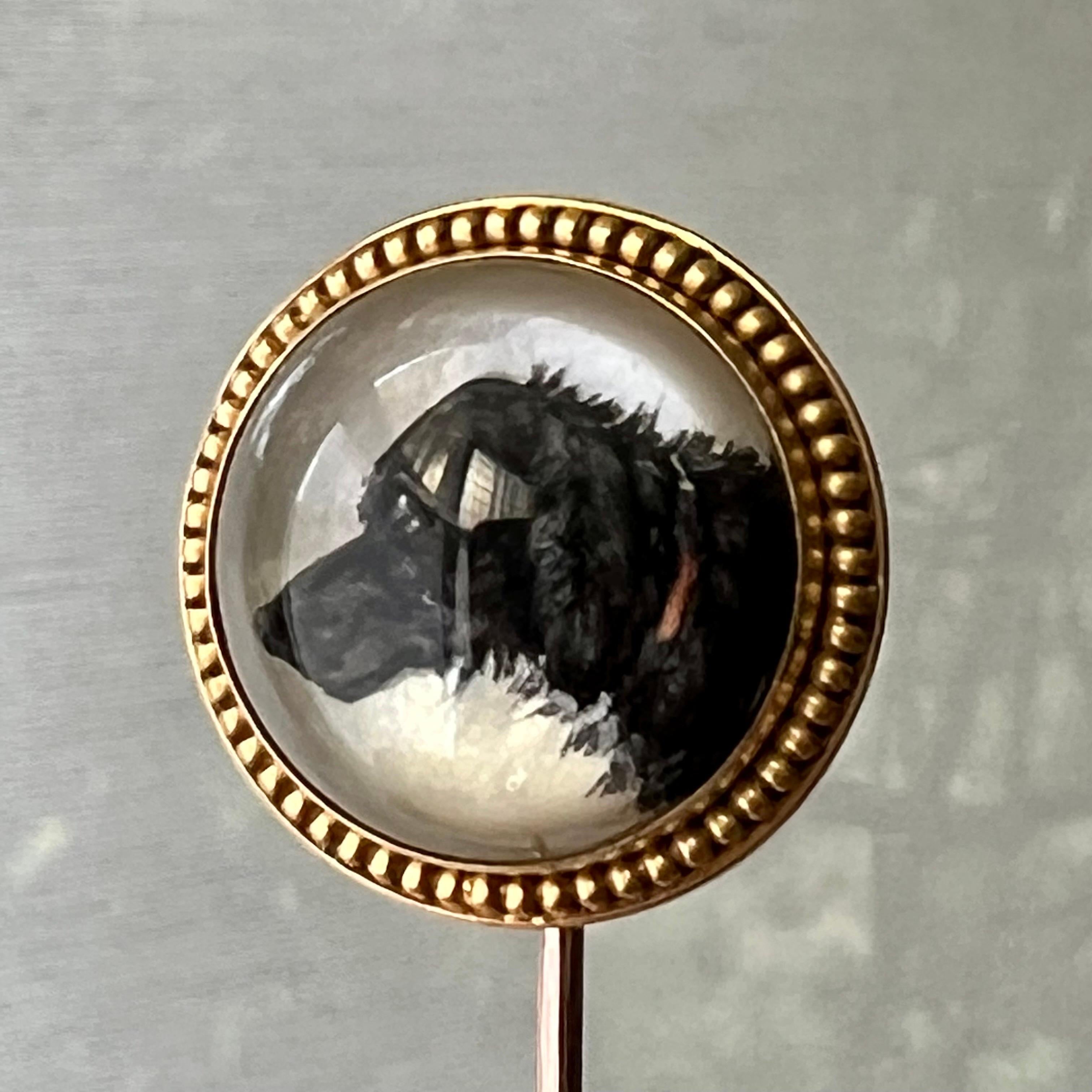 Eine antike Stichtiefdruck-Kristall-Anstecknadel, die einen Jagdhund abbildet. Das Hundebild wurde auf einem rückseitig geschliffenen Kristall gemalt und hat einen Hintergrund aus Perlmutt. Das Hundekristallbild ist in eine granulierte 14-karätige
