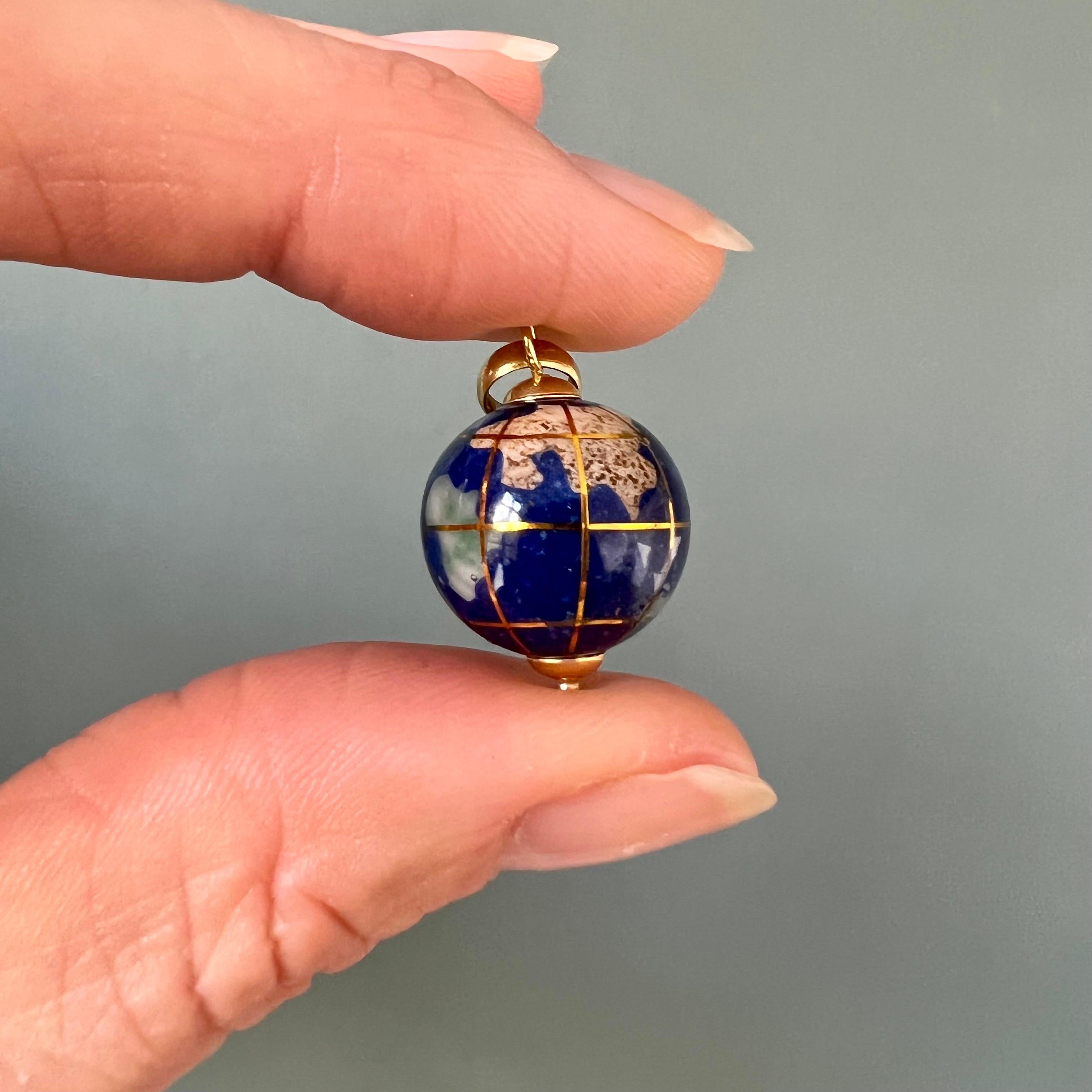 A beautiful 18 karat gold pendant in the shape of a globe, made of porcelain containing several continents and islands. These are inlaid with mother-of-pearl and semi-precious stones, including Peridot, Aventurine and Jasper. The porcelain is