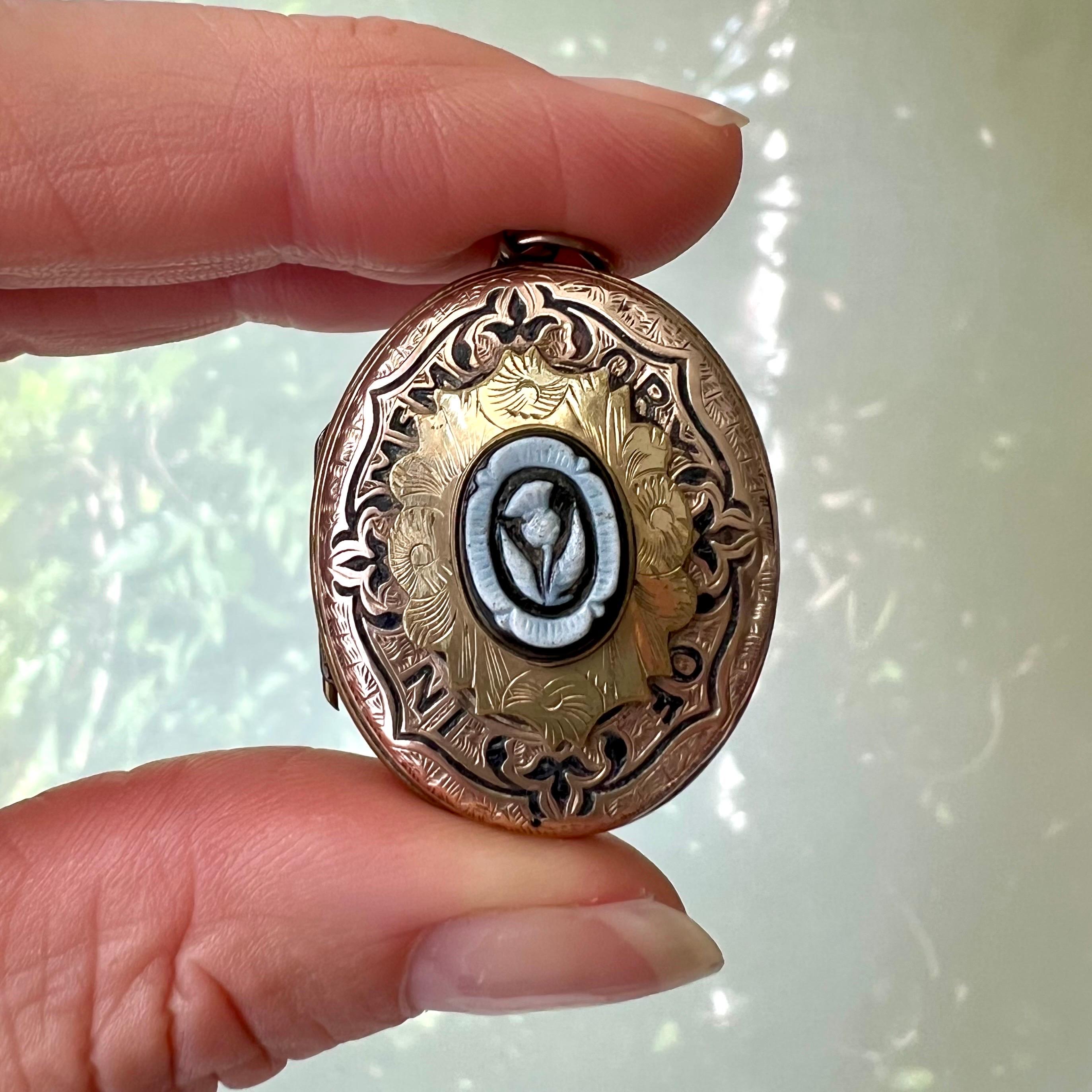 A very charming antique Victorian rose and yellow gold mourning locket. This beautiful oval locket features an engraved front and back. The front is decorated with black enamel around the center panel and engraved with the words “IN MEMORY OF”. The