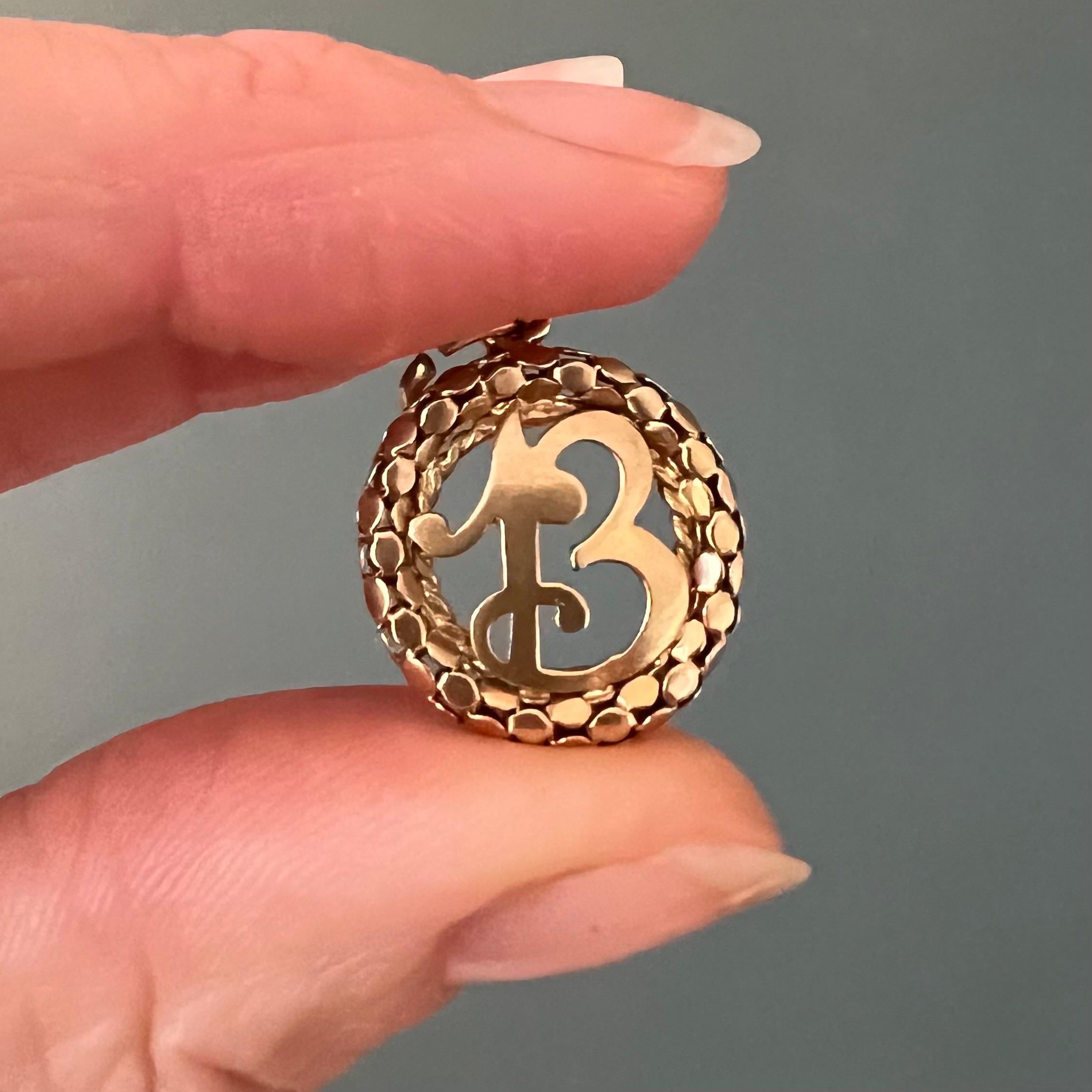 This number thirteen vintage charm pendant is created in 18 karat yellow gold. It features a rare and beautiful mesh popcorn wreath design and an ornate number 13 in the center. The mesh pop chain is a symbol of love, friendship, and connectivity.