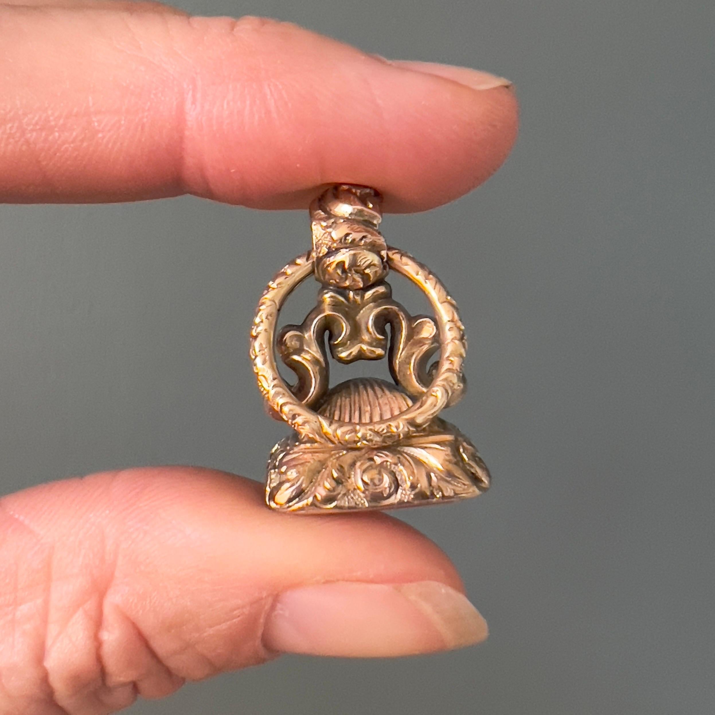 An antique early Victorian 9ct gold seal fob pendant, showcasing intricate craftsmanship. This stunning piece features classic scrolling arches leading to an integral bail, which is attached to a 14 karat gold split ring. The split ring is